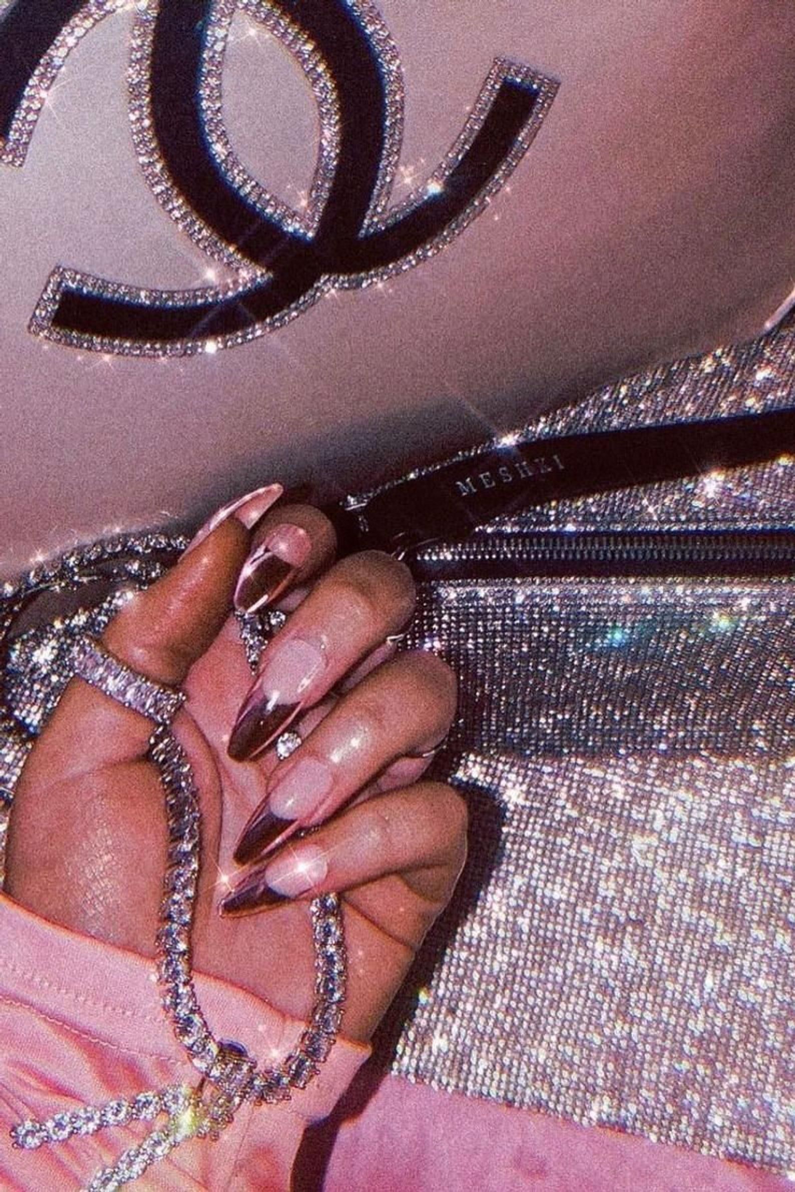 A woman with long nails holding onto her purse - Nails, bling