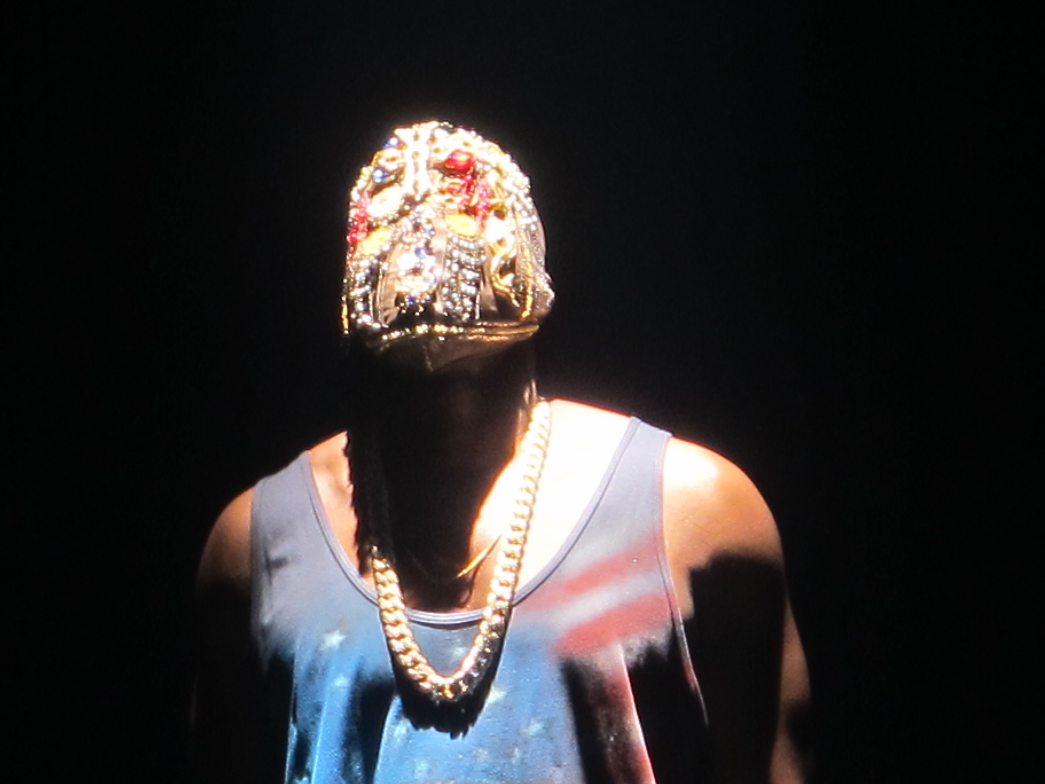 A man wearing a tank top and a gold chain around his neck. - Kanye West