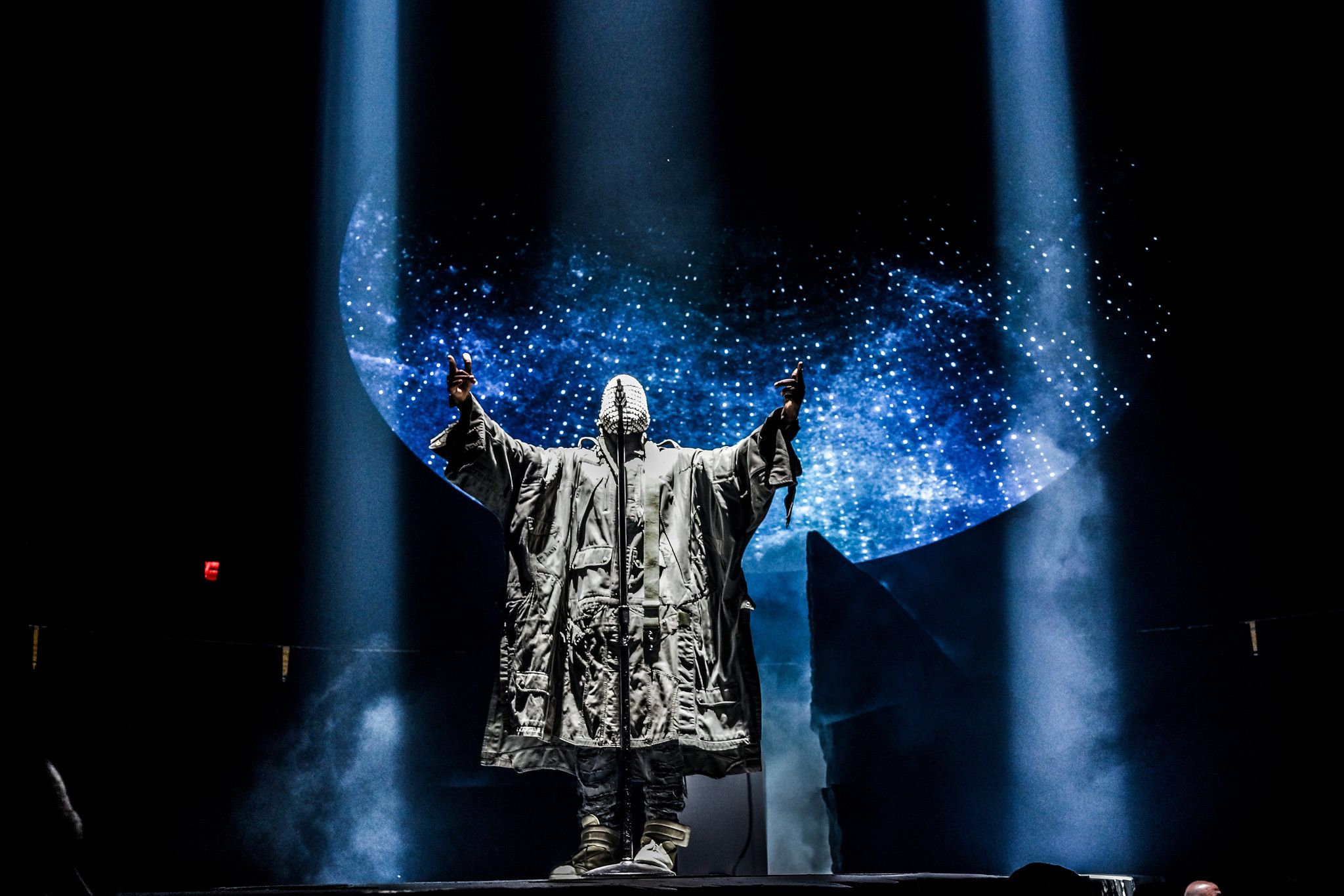 Kanye West performs on stage in a silver robe - Kanye West