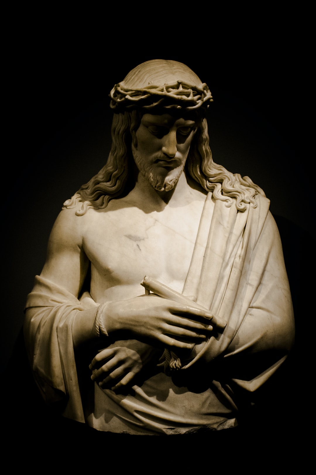 A statue of Jesus with a crown of thorns holding a cross. - Jesus