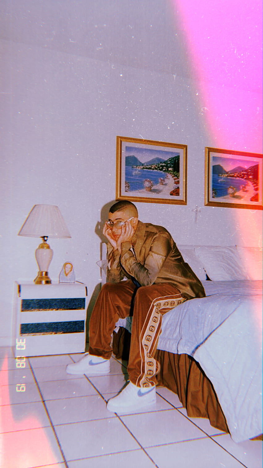 A man sitting on the bed in his room - Bad Bunny