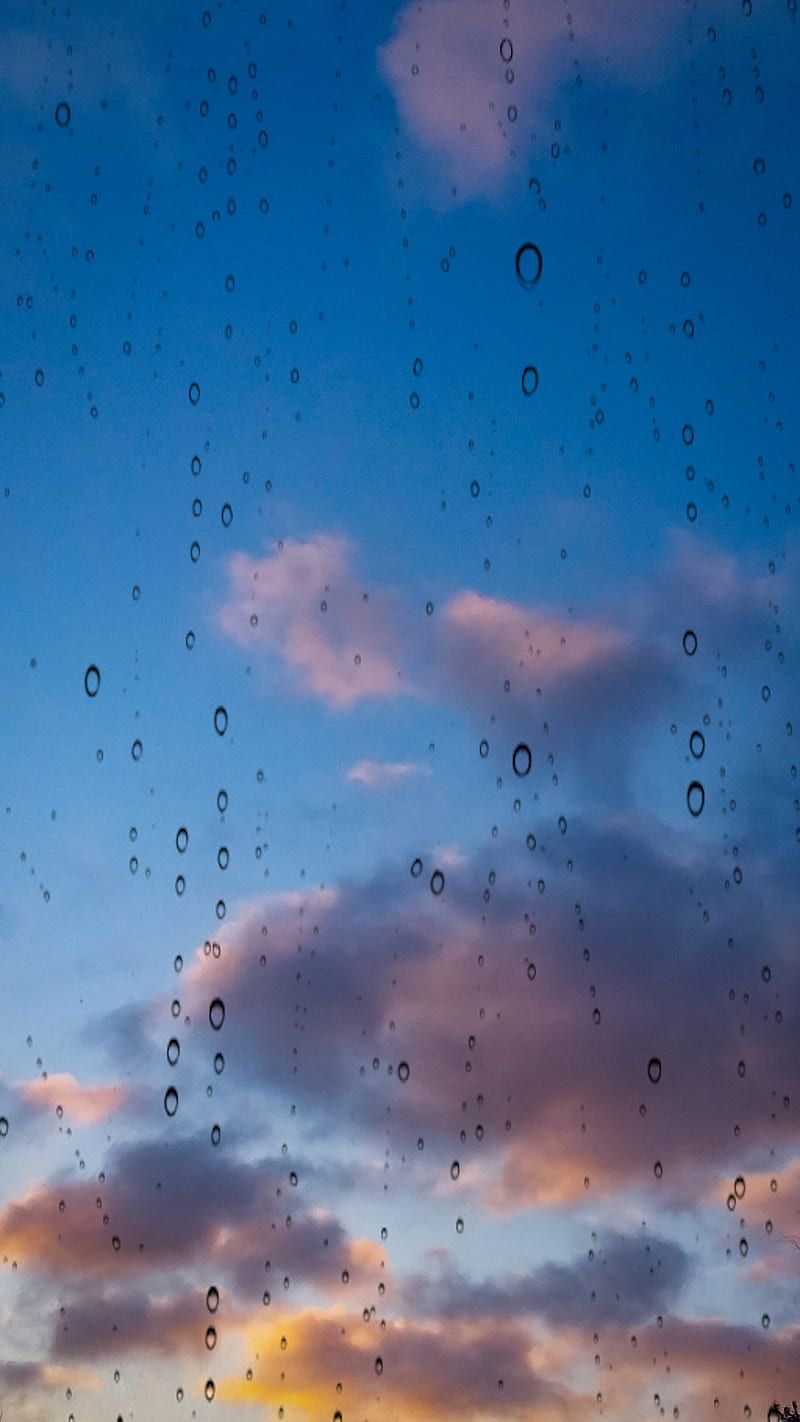 Raindrops on a window with a sunset in the background - Rain