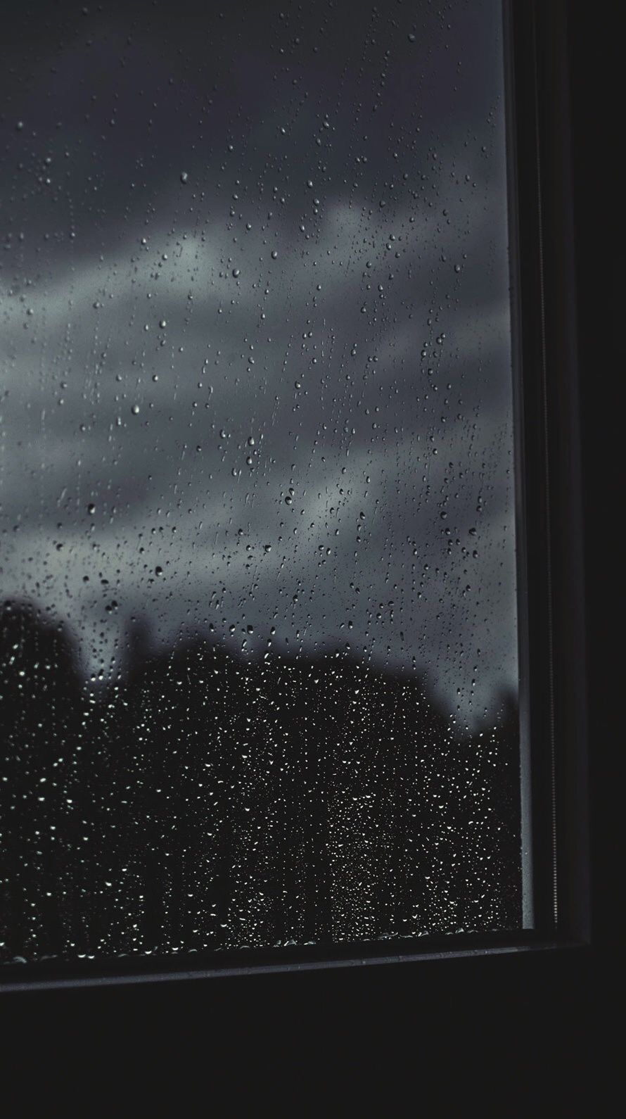 Raindrops on a window with a dark sky - Rain