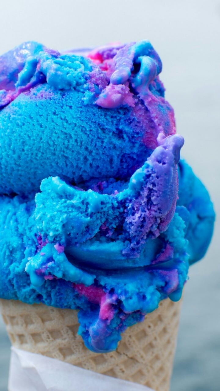 A close up of a cone with a scoop of galaxy ice cream. - Ice cream