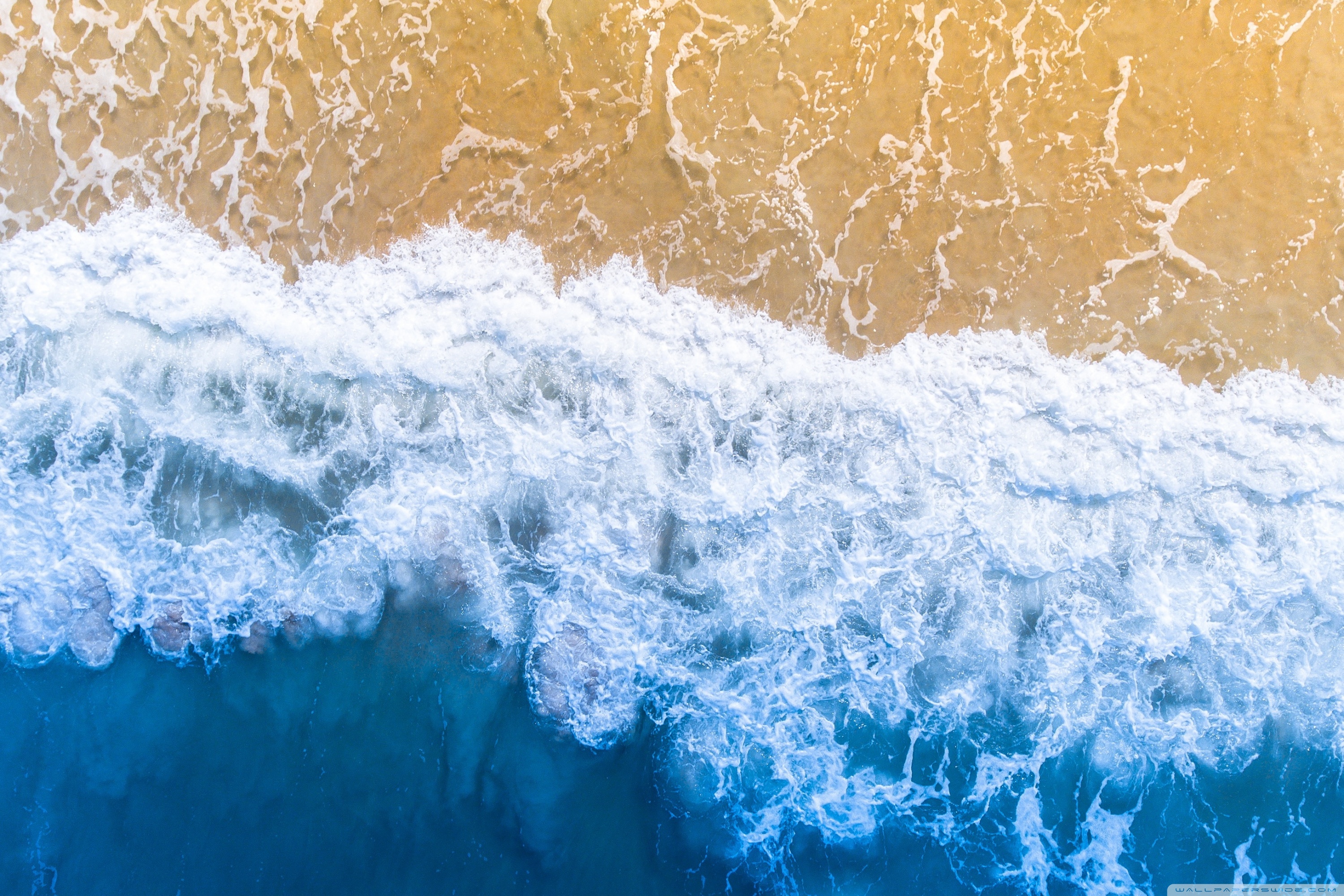 Aerial view of waves breaking on a sandy beach - Ocean