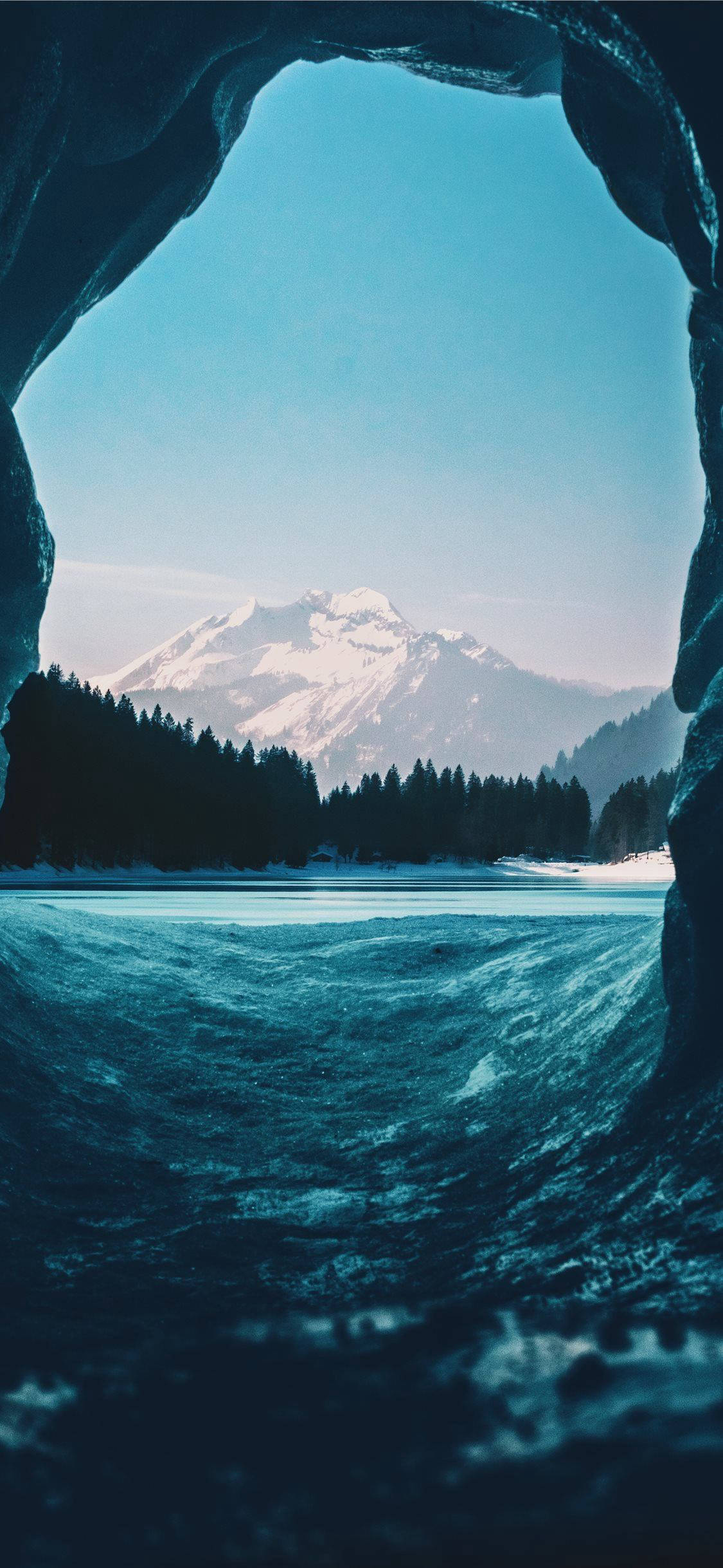 IPhone wallpaper of a snowy mountain landscape seen through a cave. - Ocean