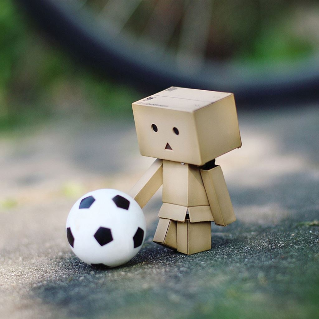 A small toy is standing next the soccer ball - Soccer