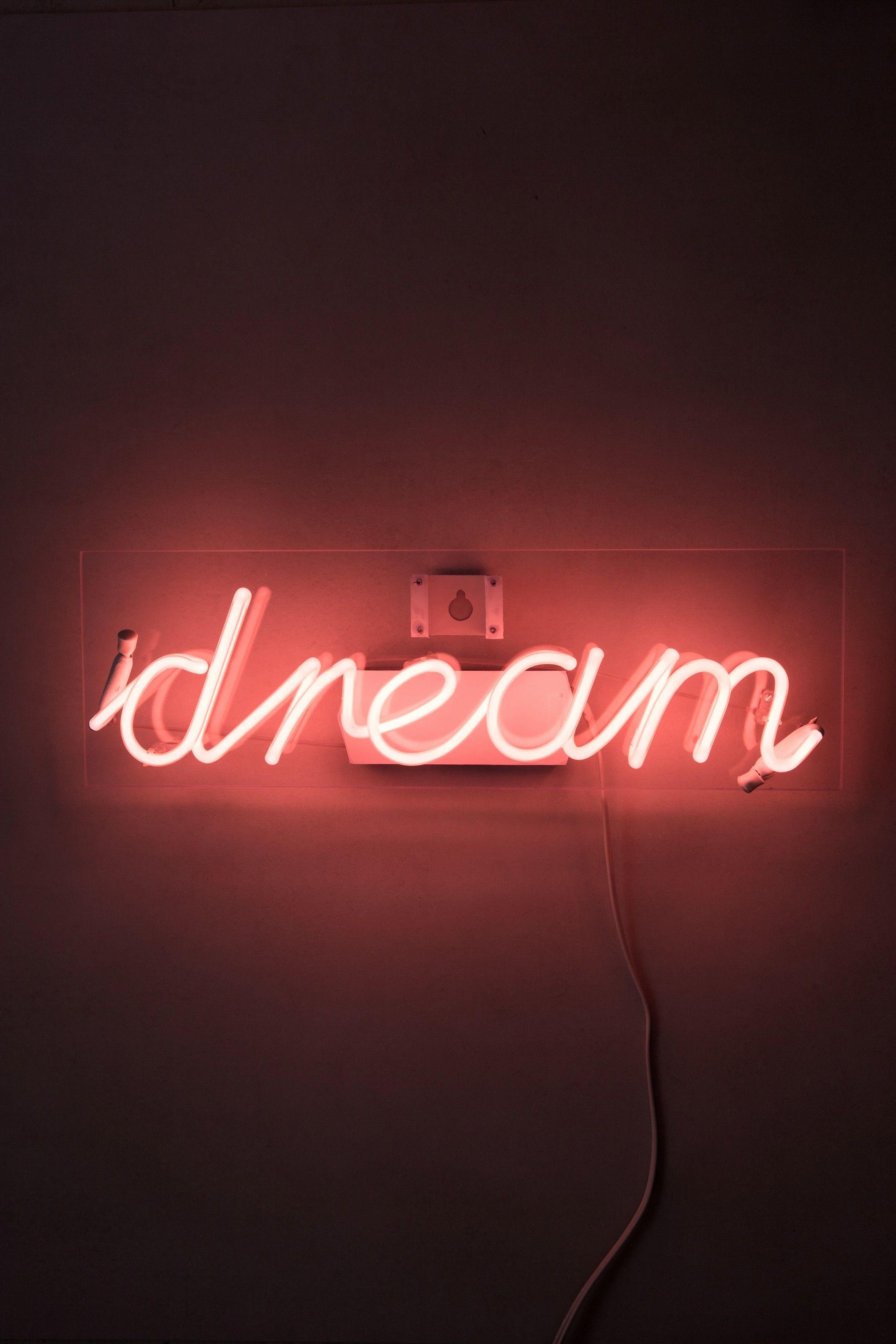 A red neon sign that says dream on a dark background - 