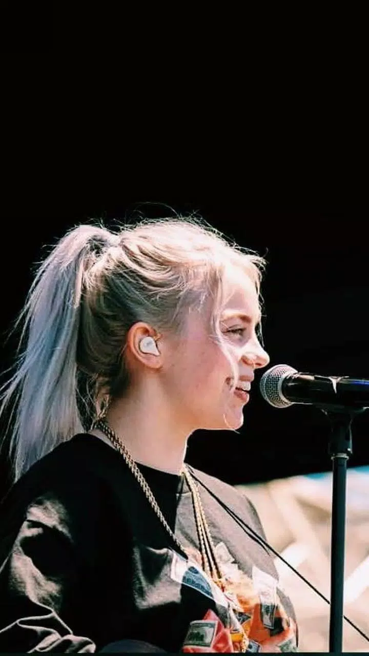 A girl with pink hair singing into microphone - Billie Eilish