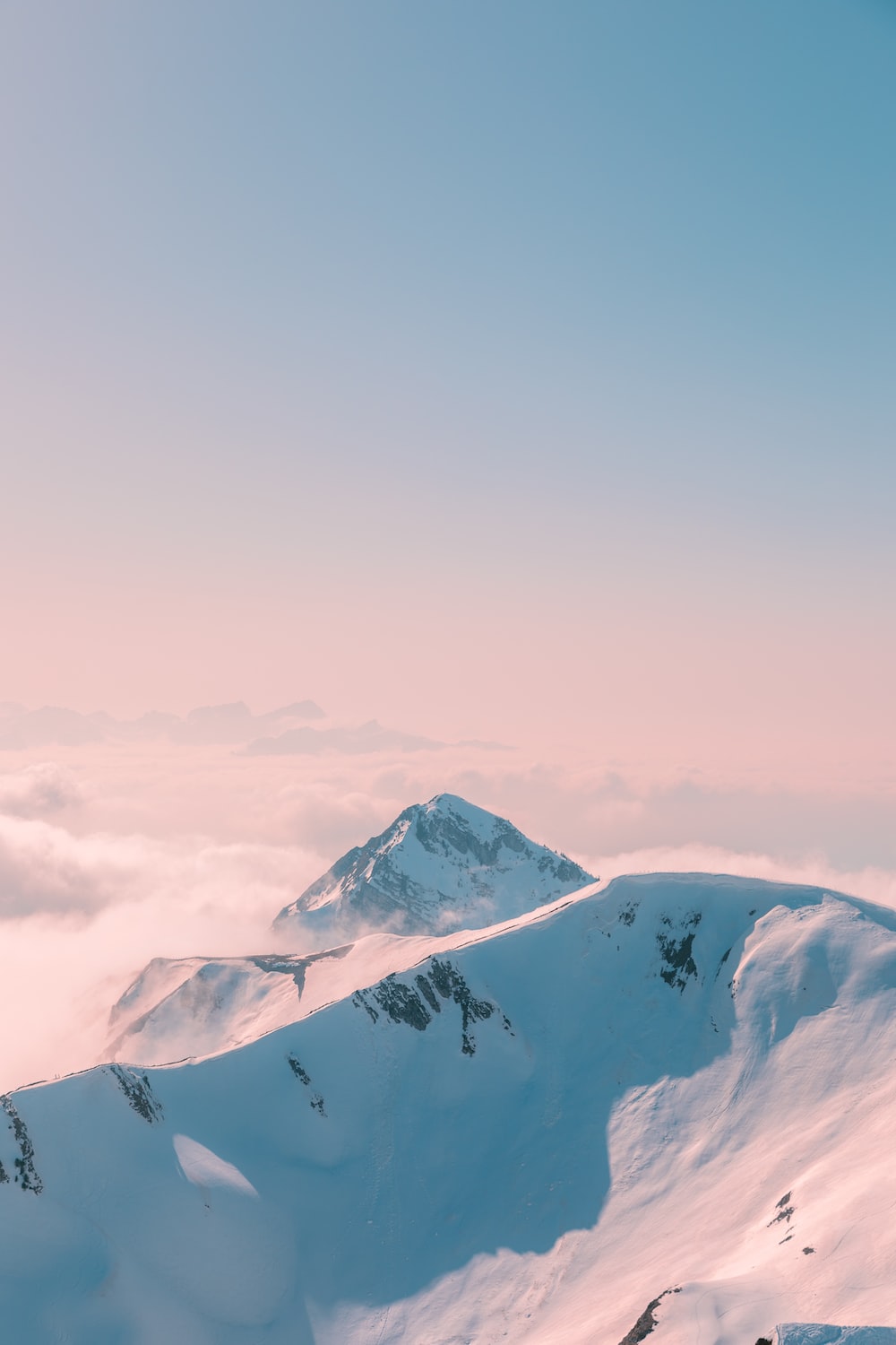 A snow covered mountain peak with a pink and blue sky - Clean