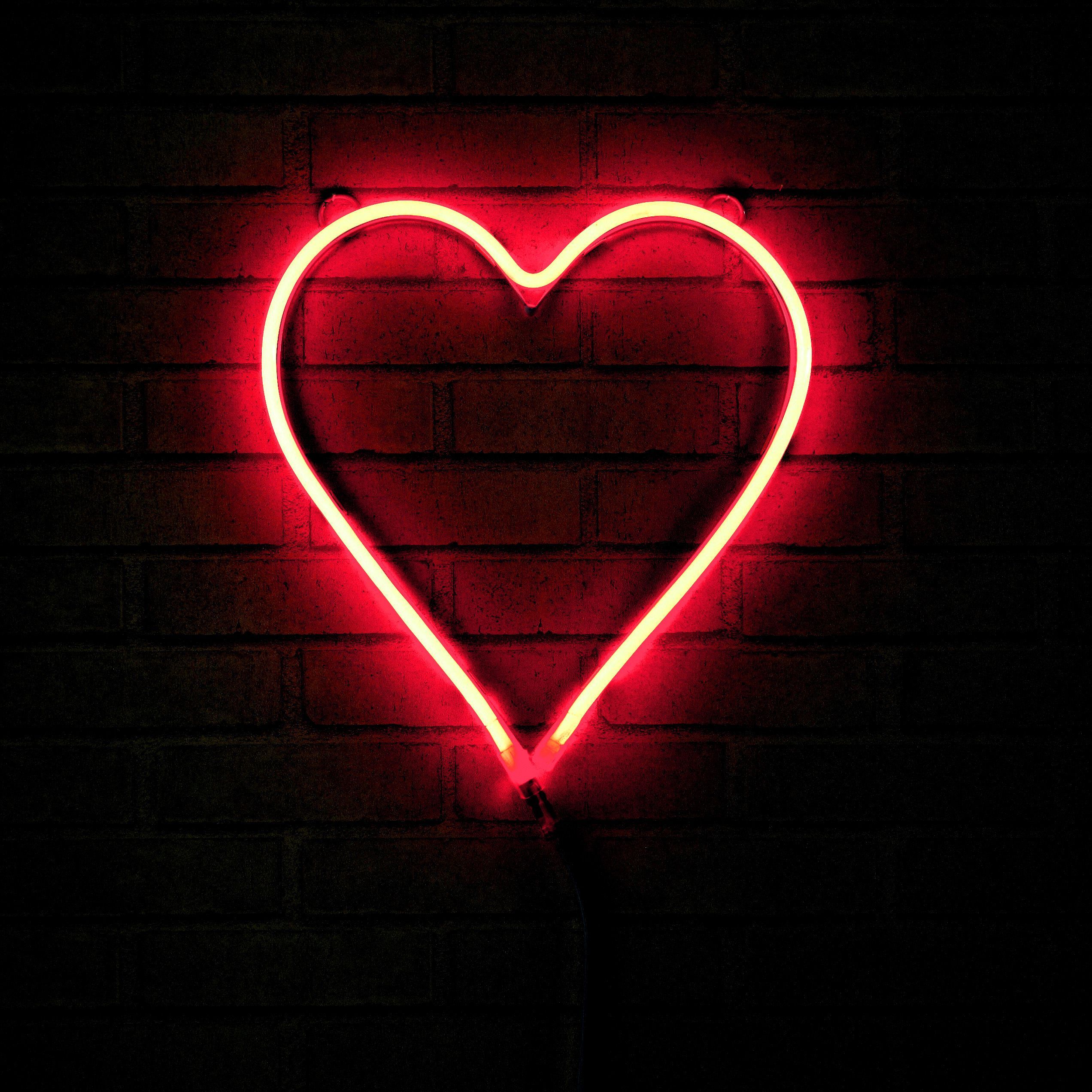 A red neon sign in the shape of a heart - 