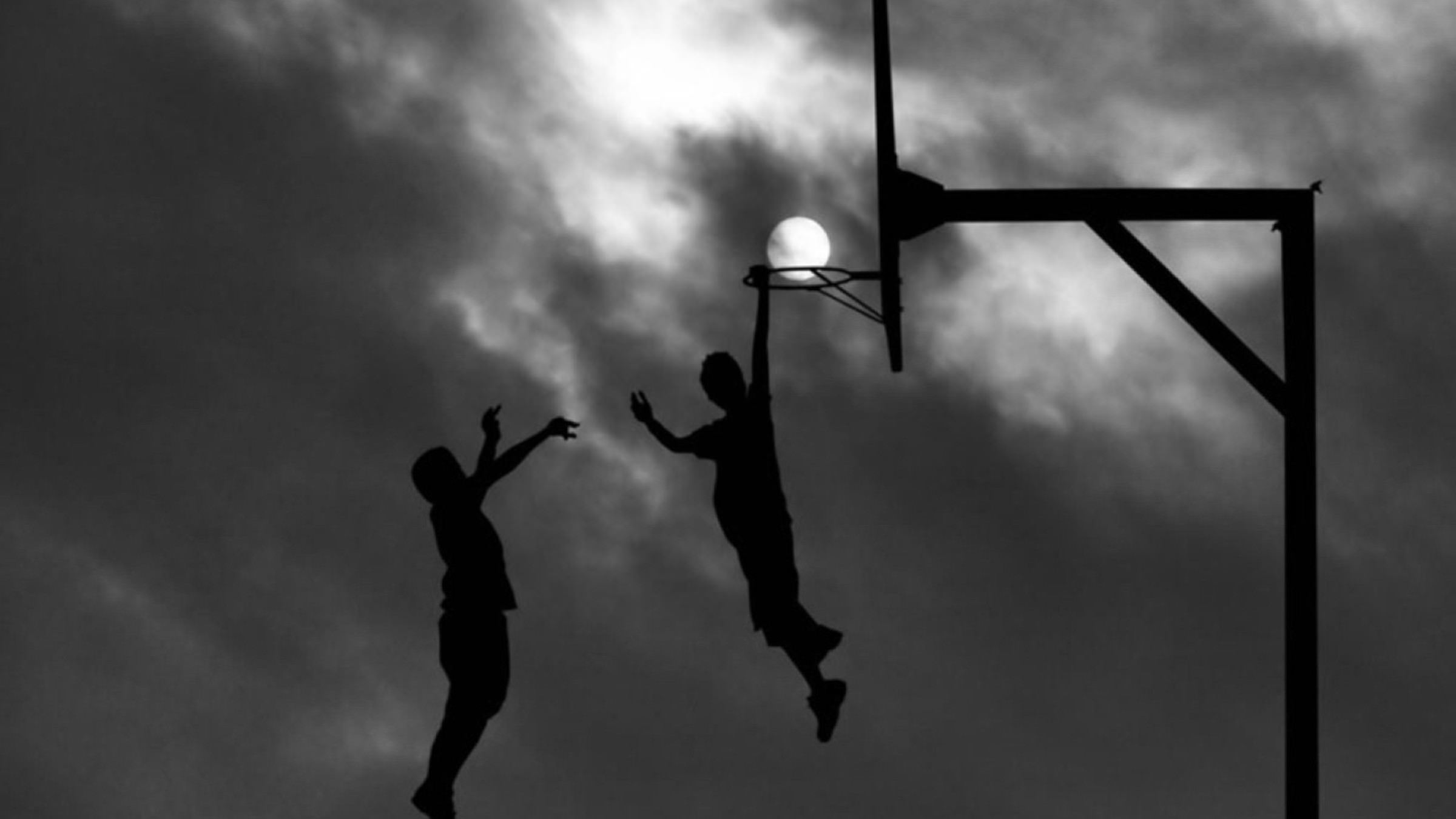 A black and white photo of two people playing basketball - Basketball