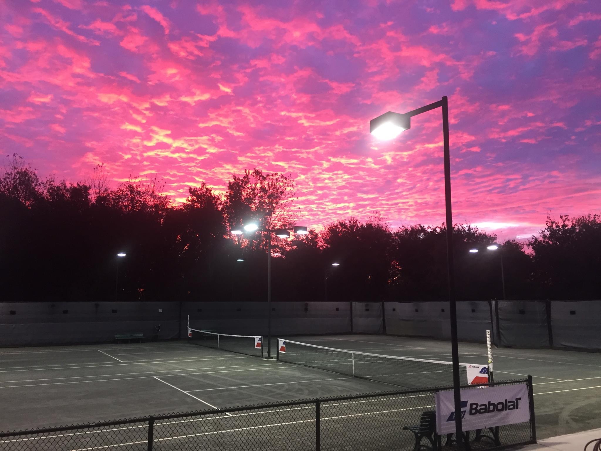 A tennis court with a beautiful sunset in the background - Tennis
