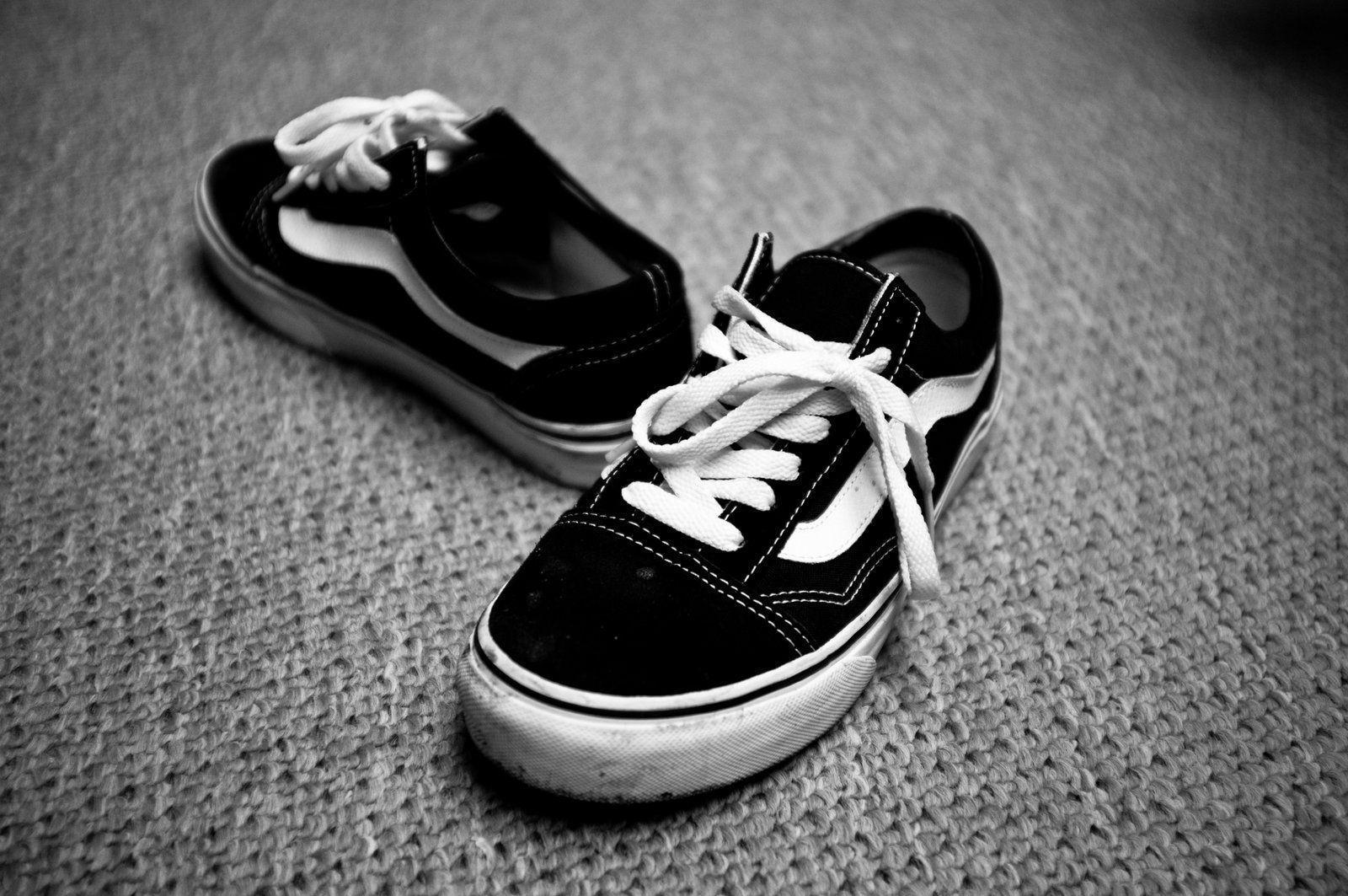 A pair of black and white sneakers are on the floor - Vans