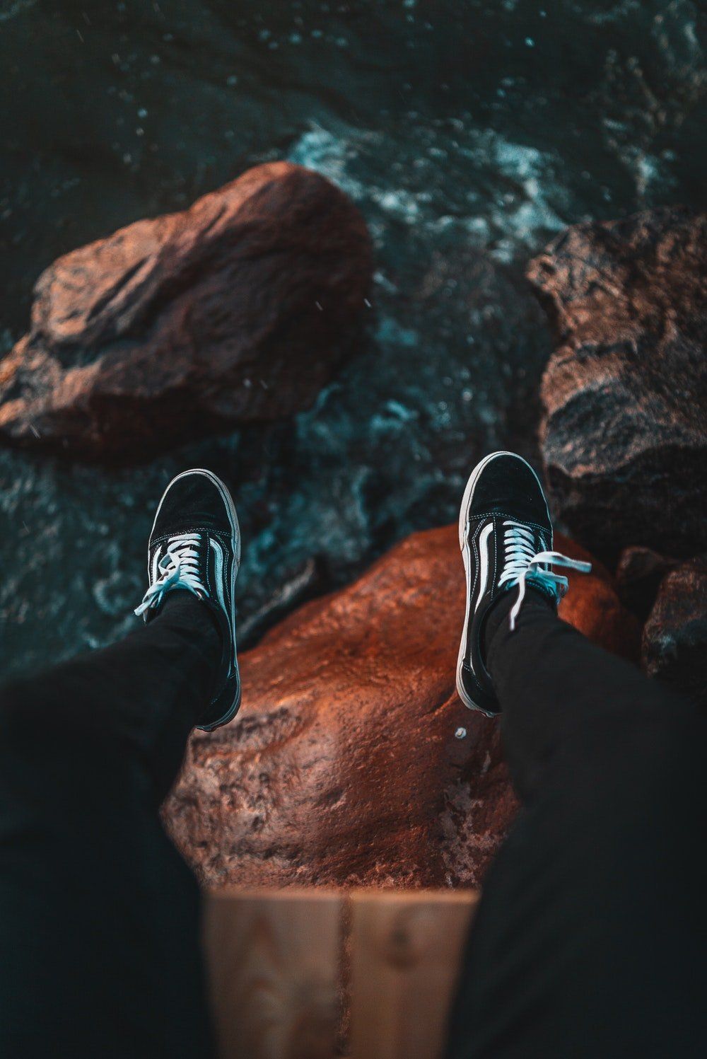 A person standing on top of rocks with their shoes - Vans