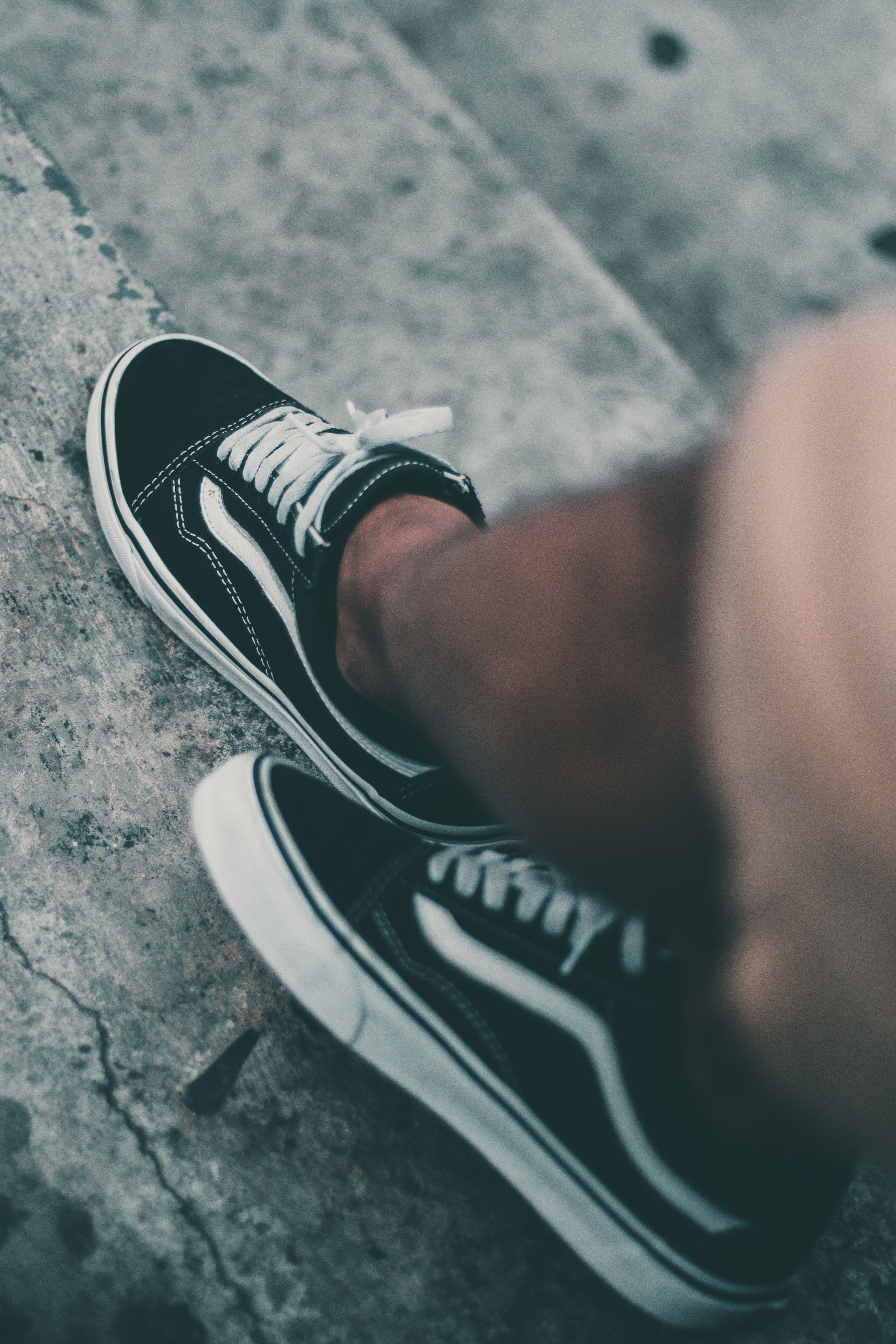 A person wearing black and white Vans sneakers. - Vans