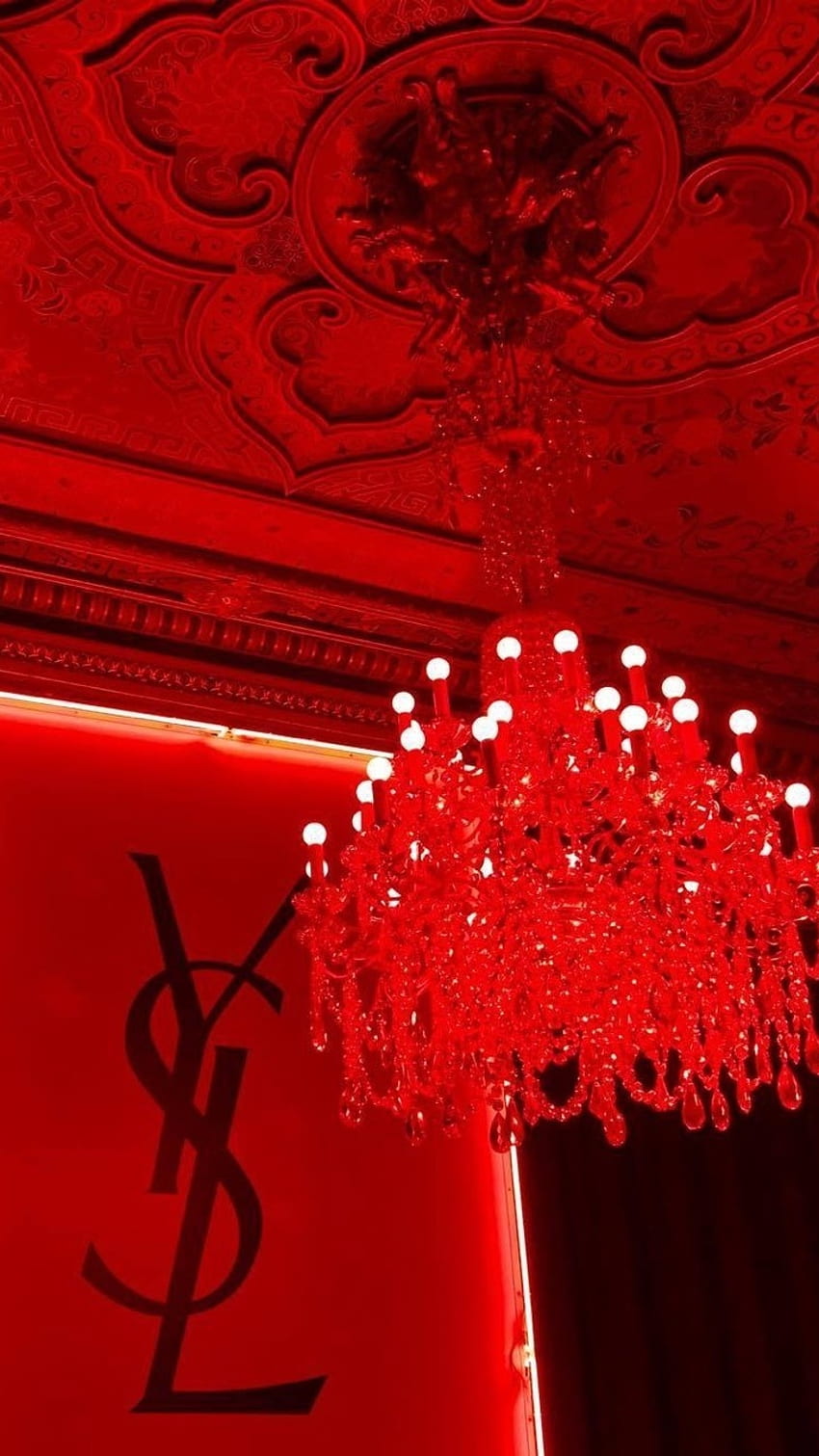A red chandelier hanging from a ceiling. - Light red