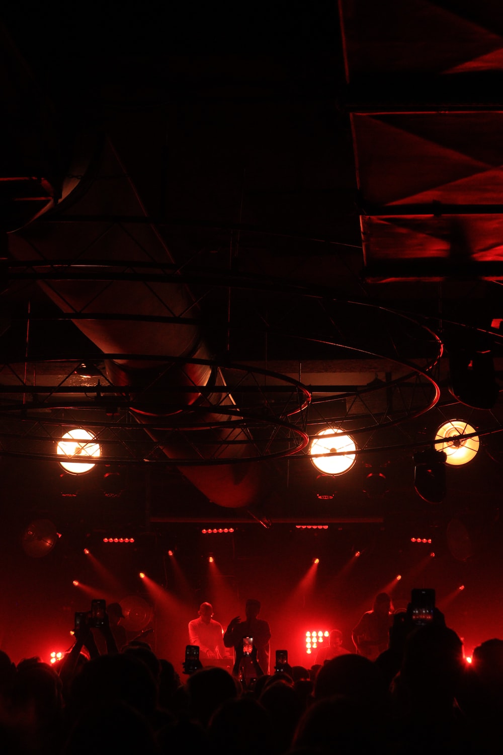 A band performing on stage with red lights and smoke. - Light red