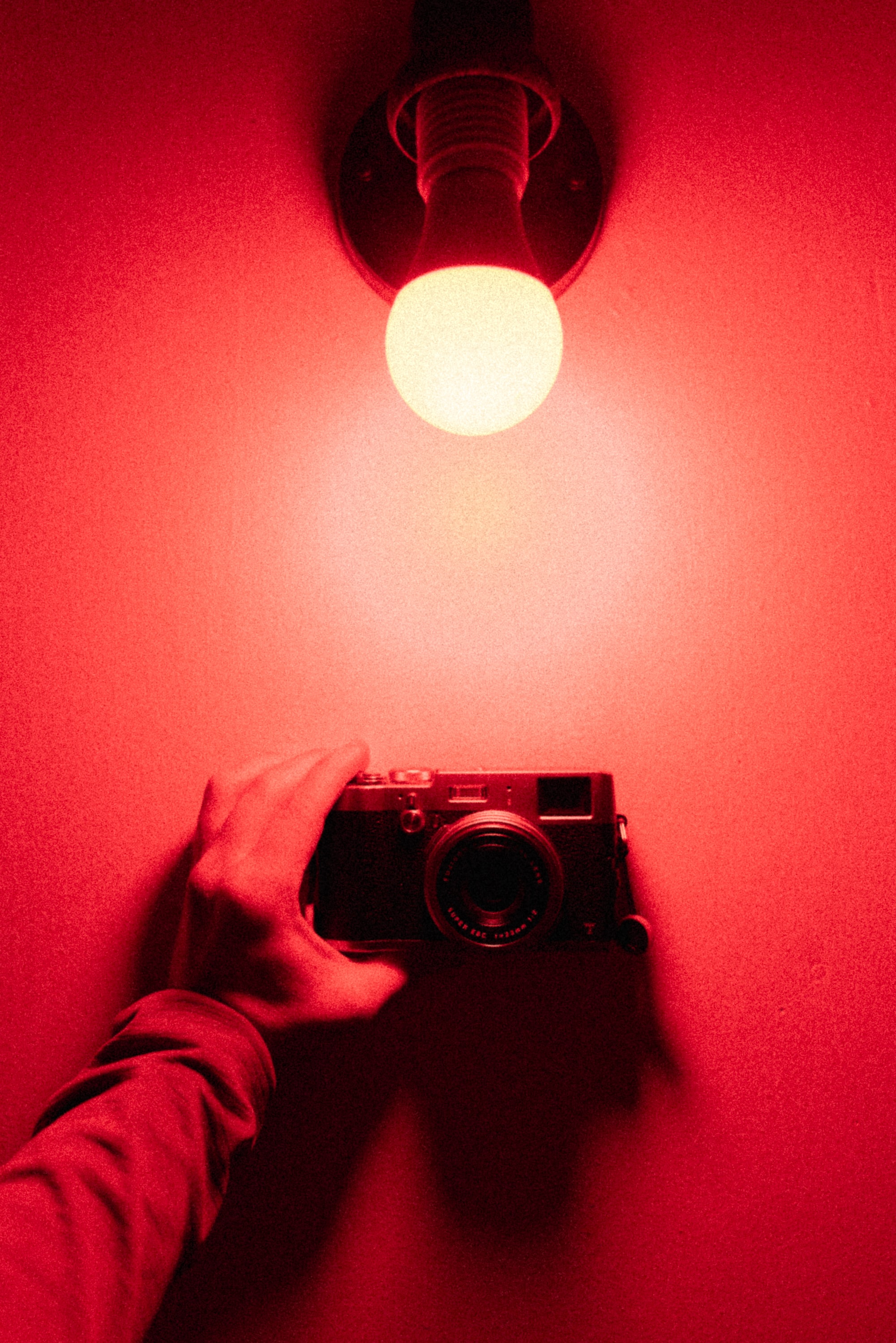 A person holding a camera in a red room - Light red