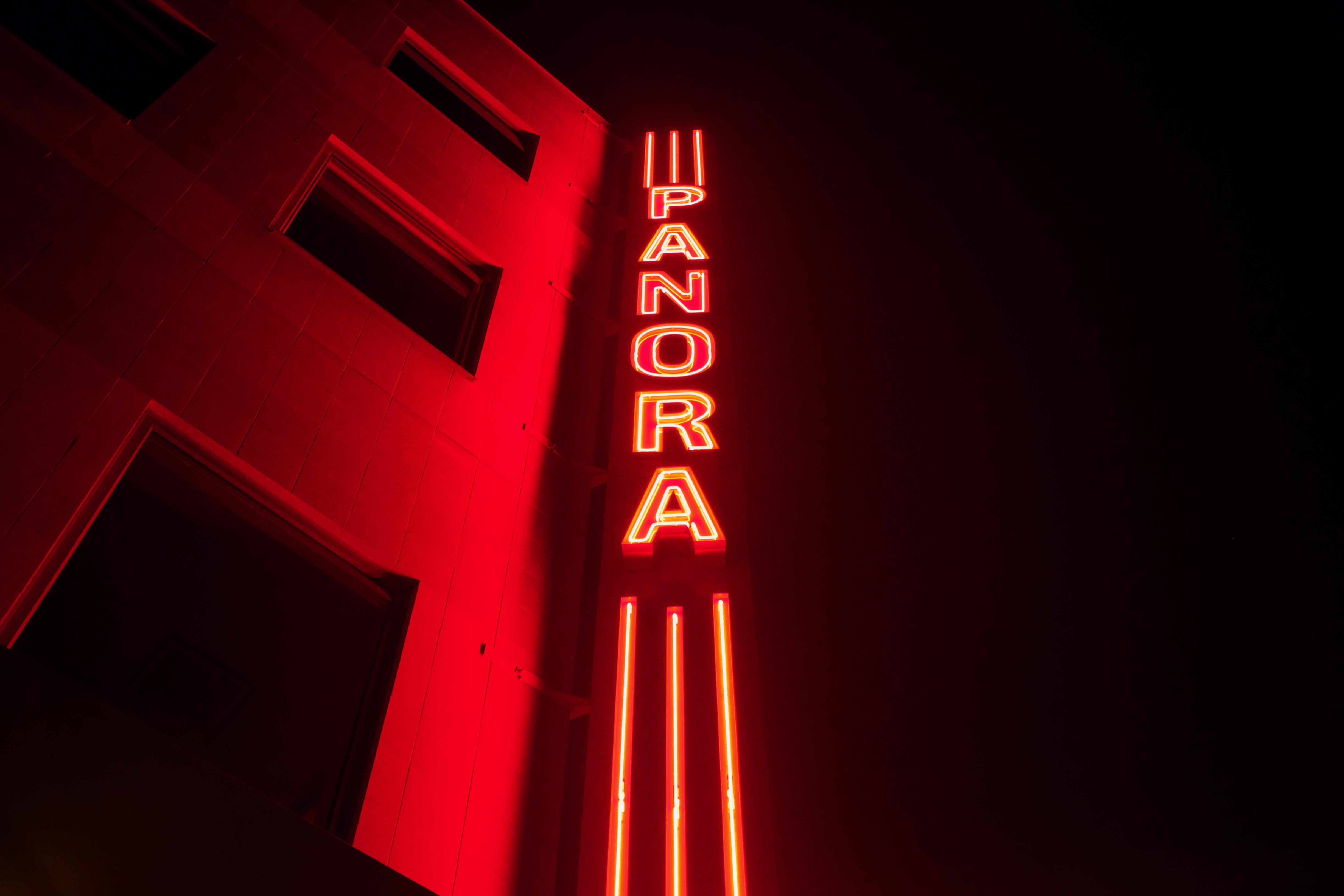 A red neon sign that is on the side of building - Light red