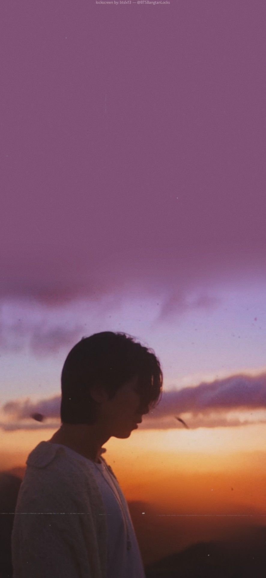 A purple and orange sunset with a boy looking down at the ground. - Indigo
