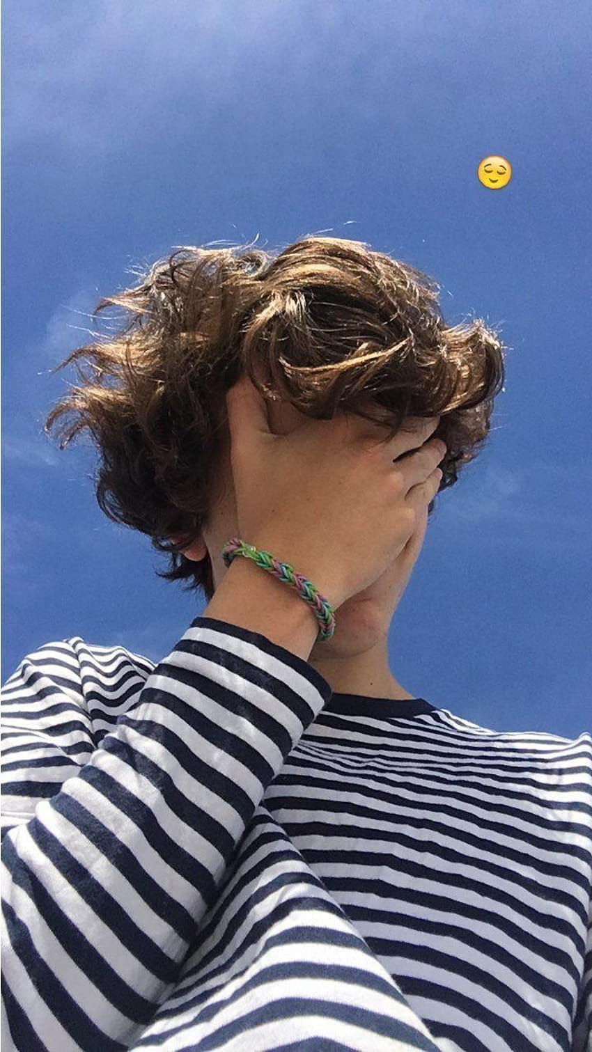 A boy with his hands over face in front of blue sky - Timothee Chalamet