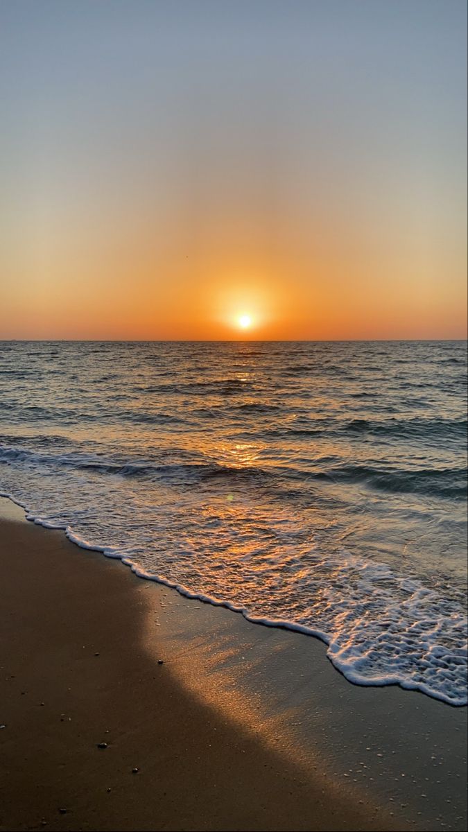 A beautiful sunset at the beach with the sun setting behind the ocean - Sunrise