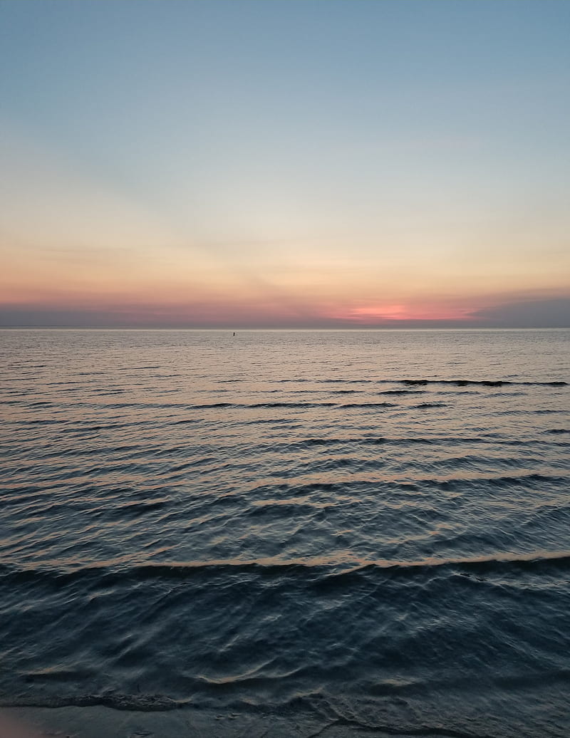 A person standing on the beach looking out at sunset - Sunrise