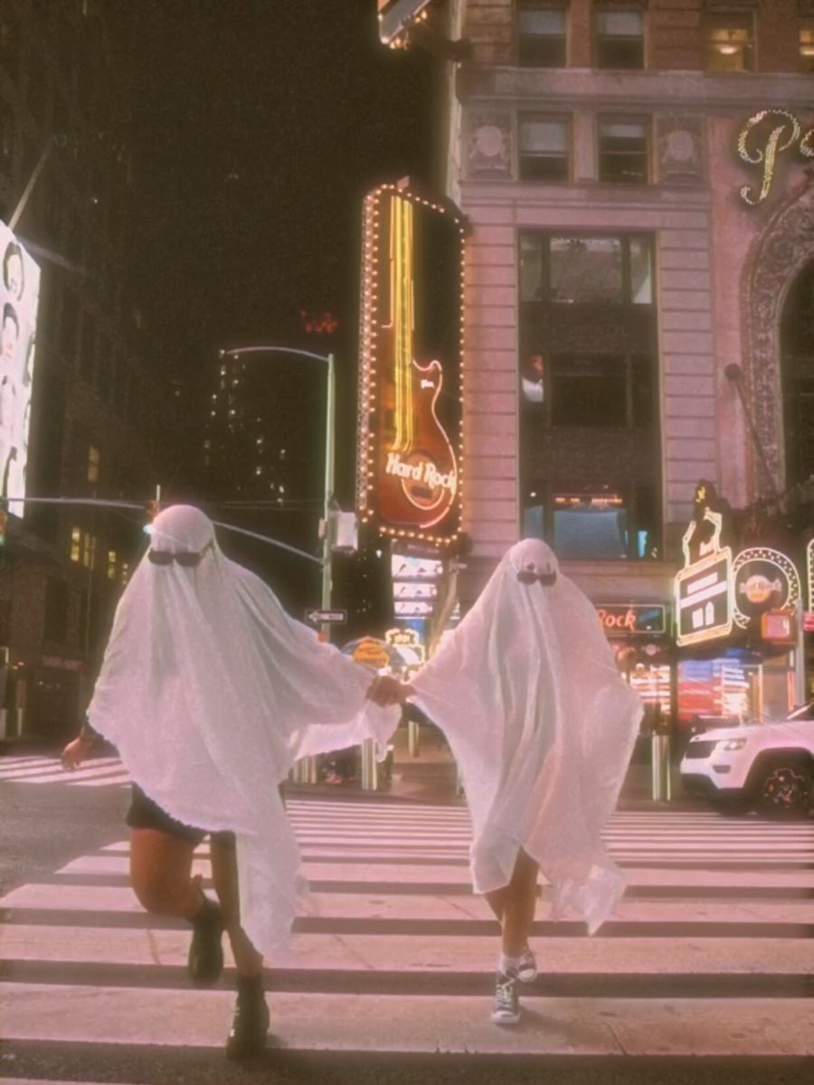 Two people dressed in white ghost costumes crossing the street - TikTok