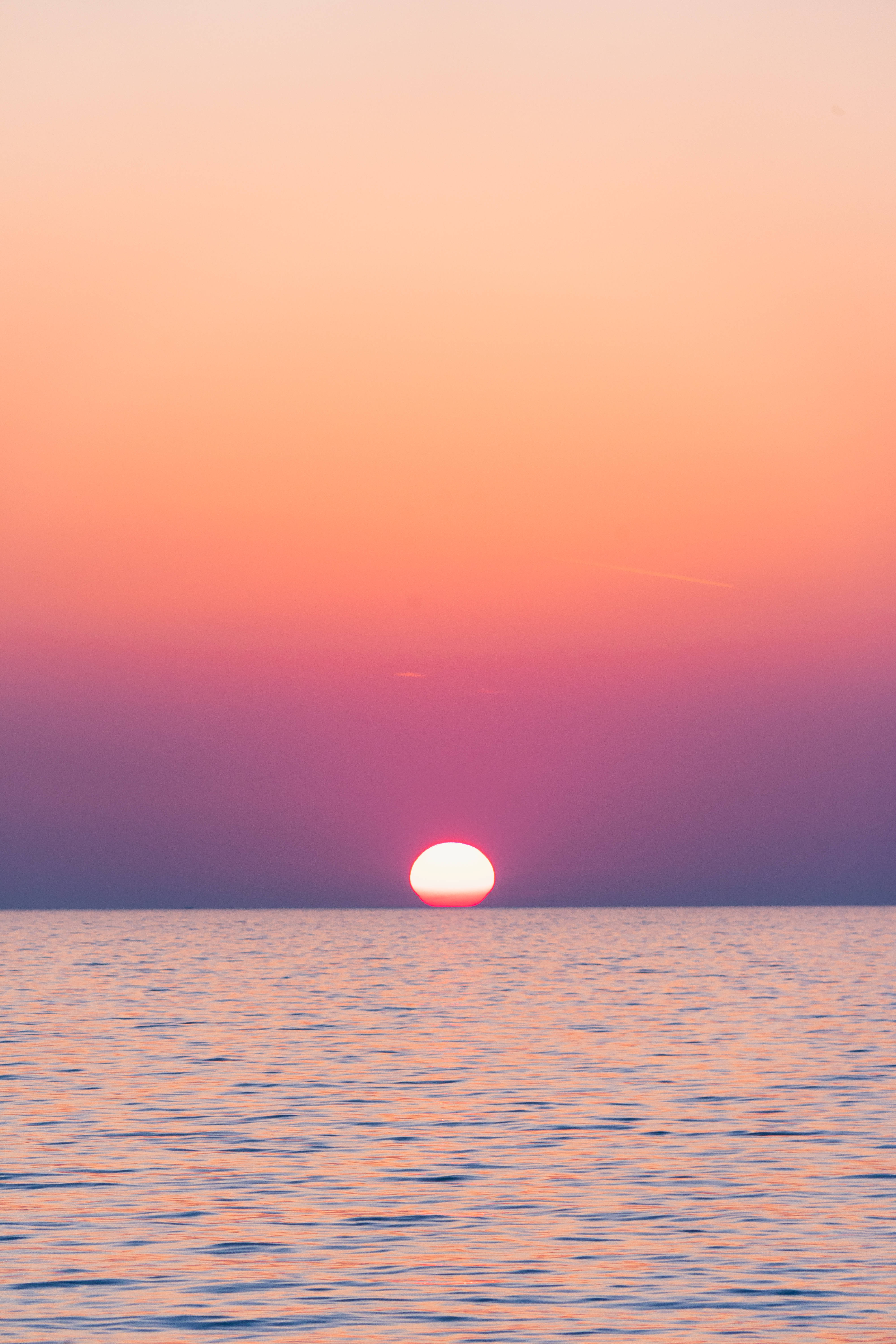 A sunset over the sea, with the sun on the horizon and the sea in the foreground. - Sunset