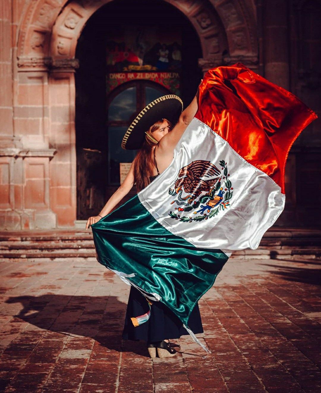 A woman is holding up the mexican flag - Mexico