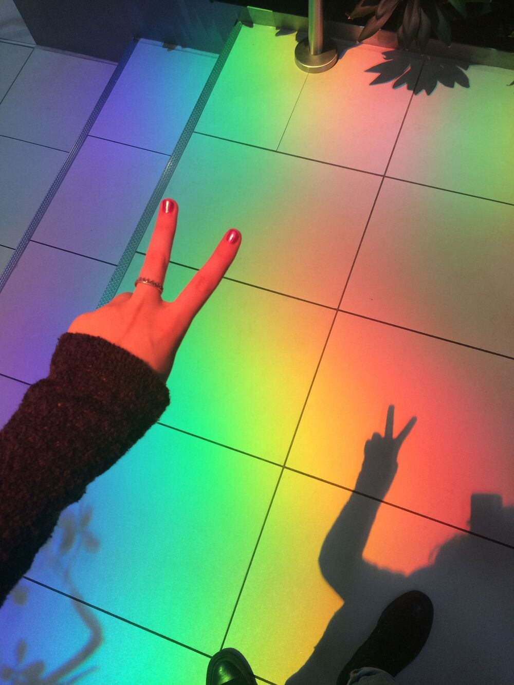 A person is making the peace sign on top of some colored tiles - Rainbows