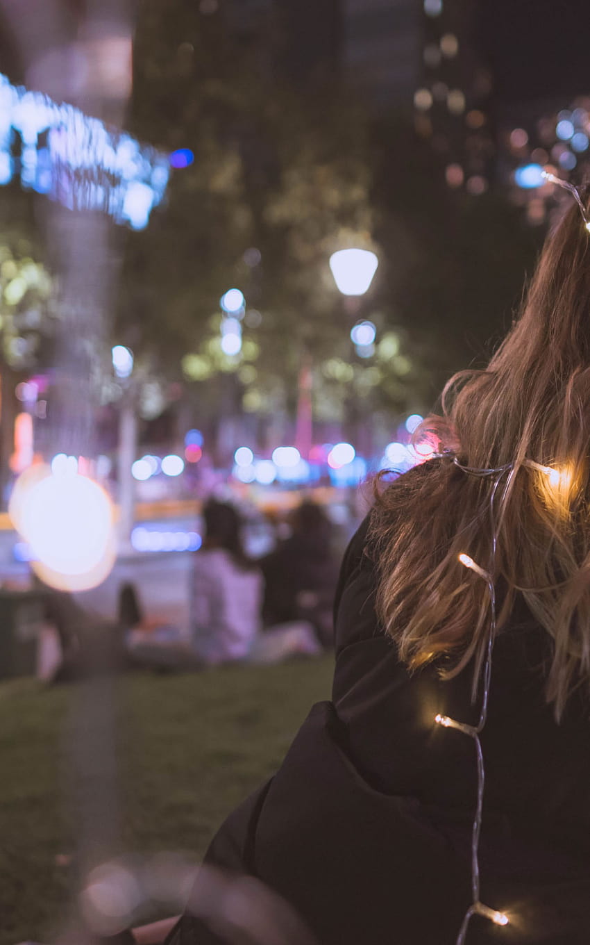 A woman sitting on the ground with her hair in lights - Blurry