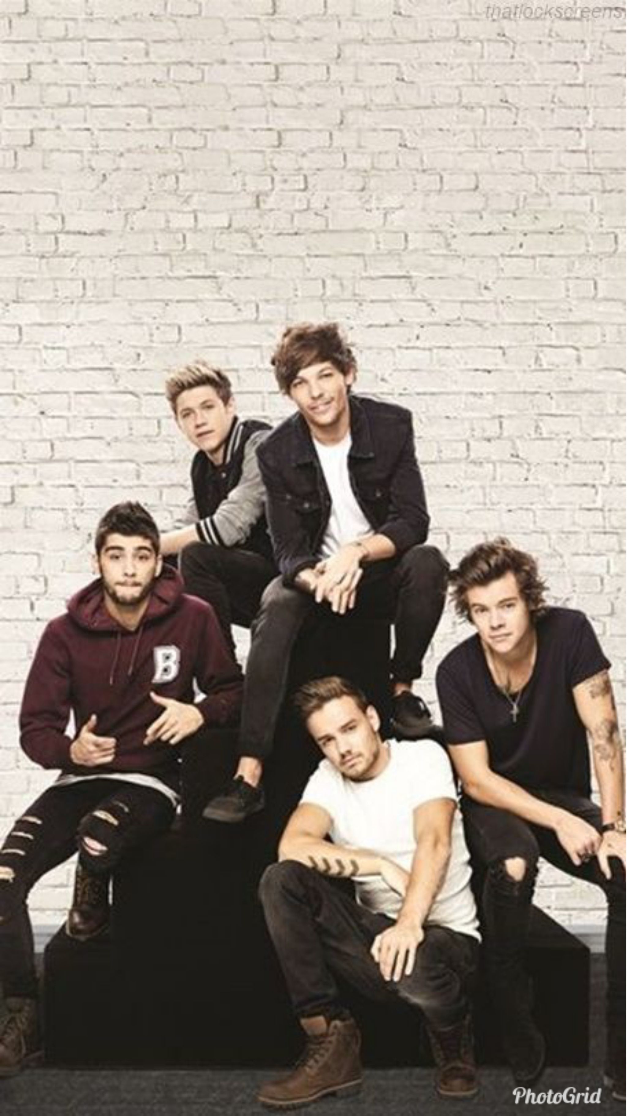 One Direction members sitting on a bench in front of a brick wall - One Direction
