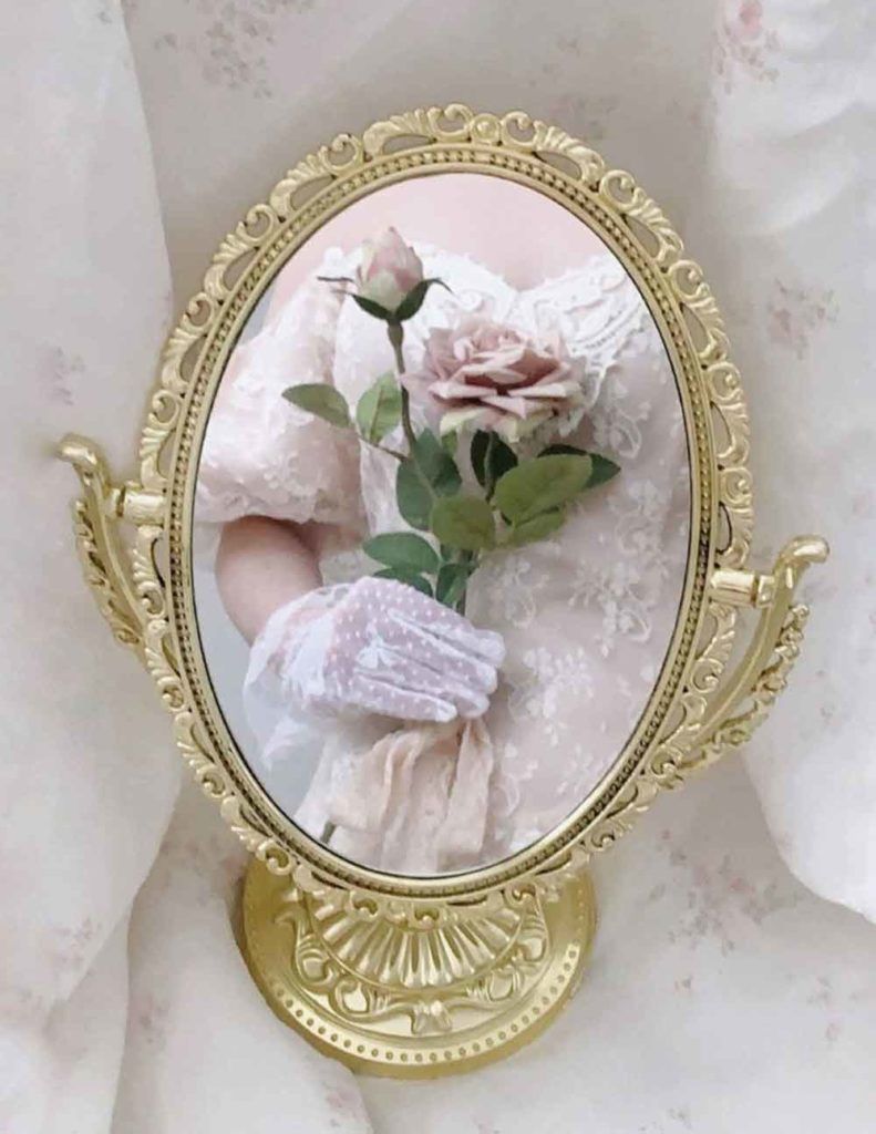 A woman holding flowers in her hand is reflected on the mirror - Royalcore