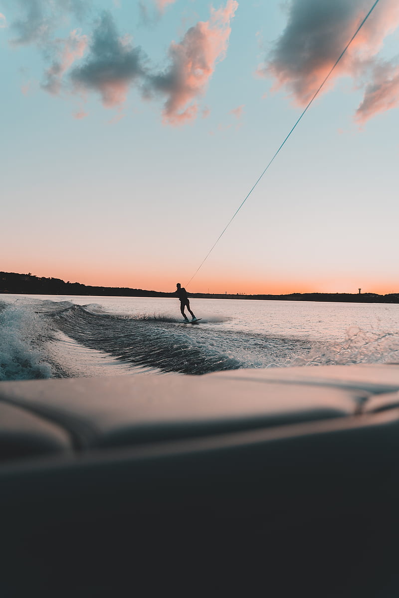 A person water skiing on a lake during sunset - Surf