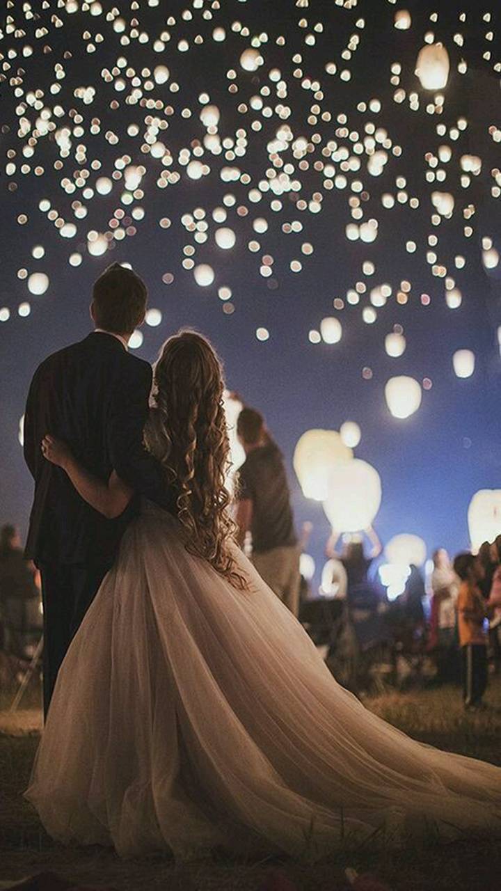 A bride and groom are standing in the dark with lanterns - Wedding