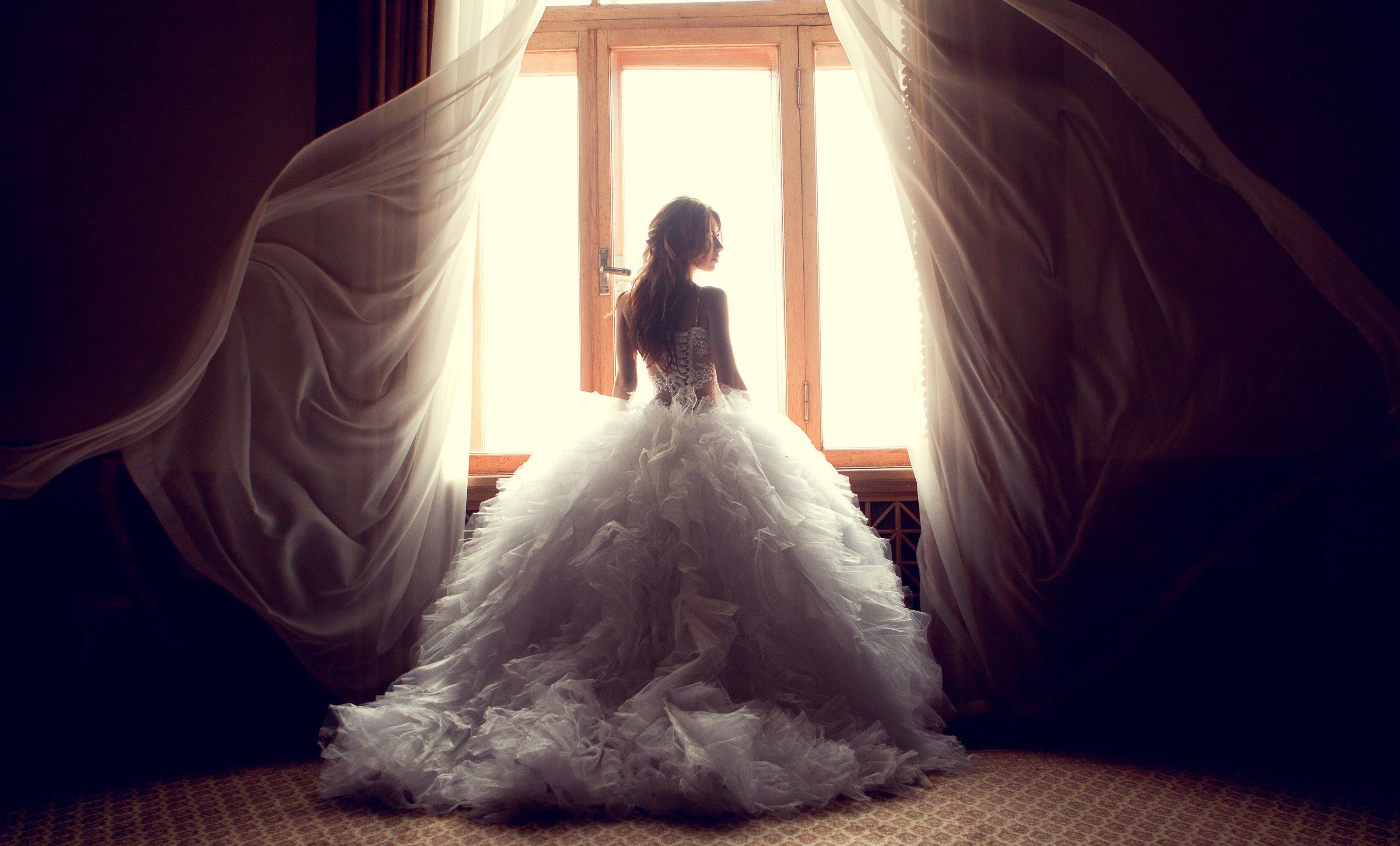 A woman in her wedding dress standing by the window - Wedding