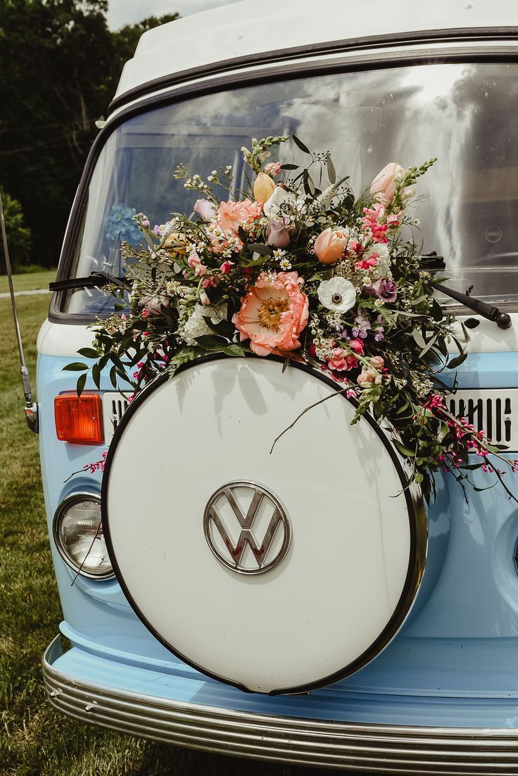A blue and white VW camper van with a flower arrangement on the back - Wedding