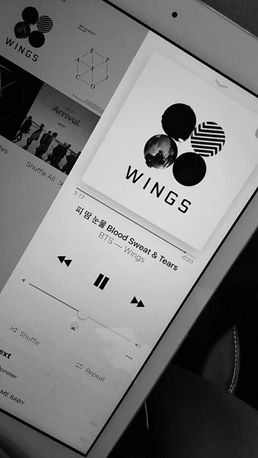 An iPhone screen displays the album cover for Wings by BTS. - Korean