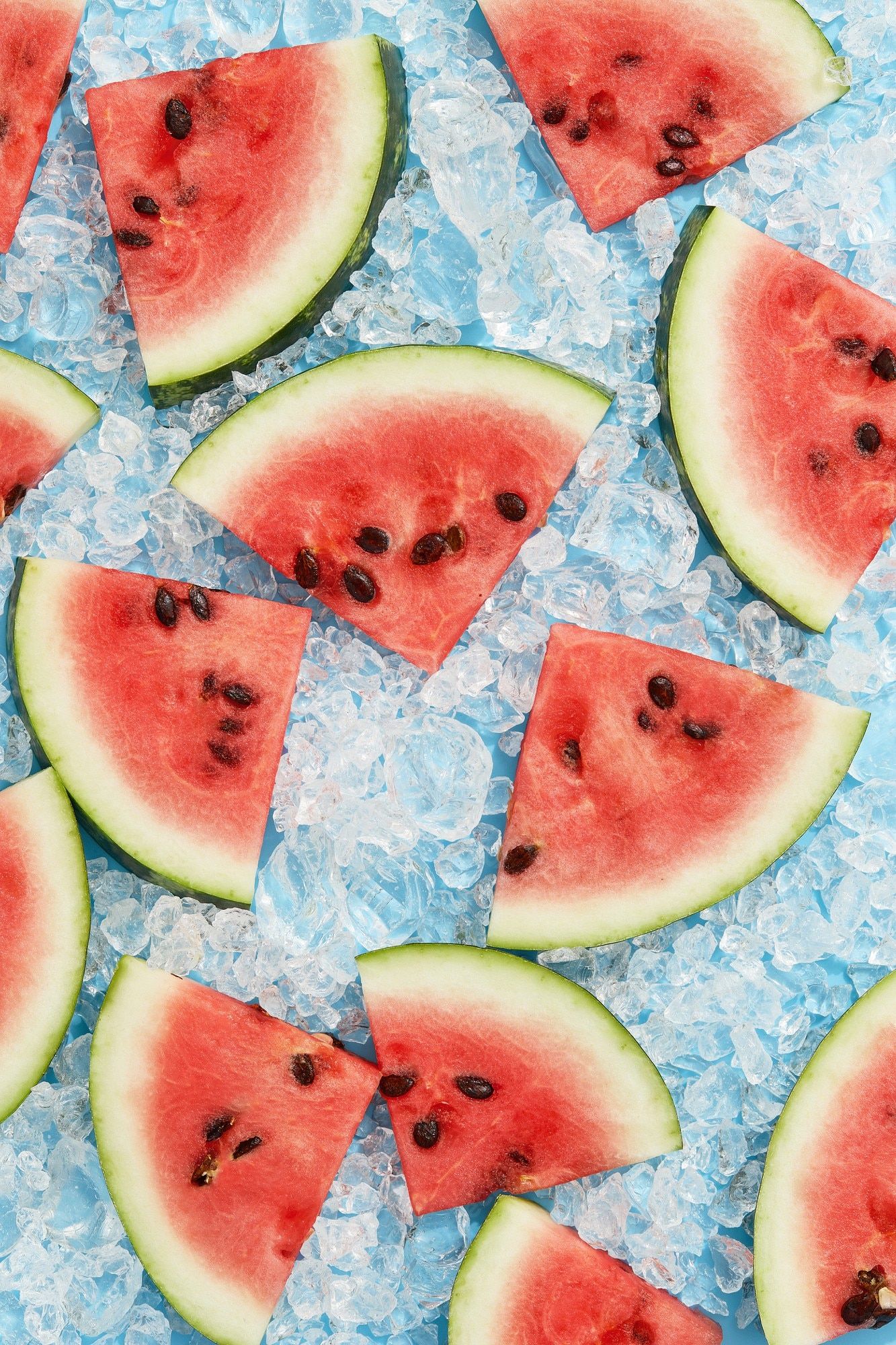Premium Photo. Summer creative wallpaper watermelon pattern with sunlight sliced fruit with ice on blue background