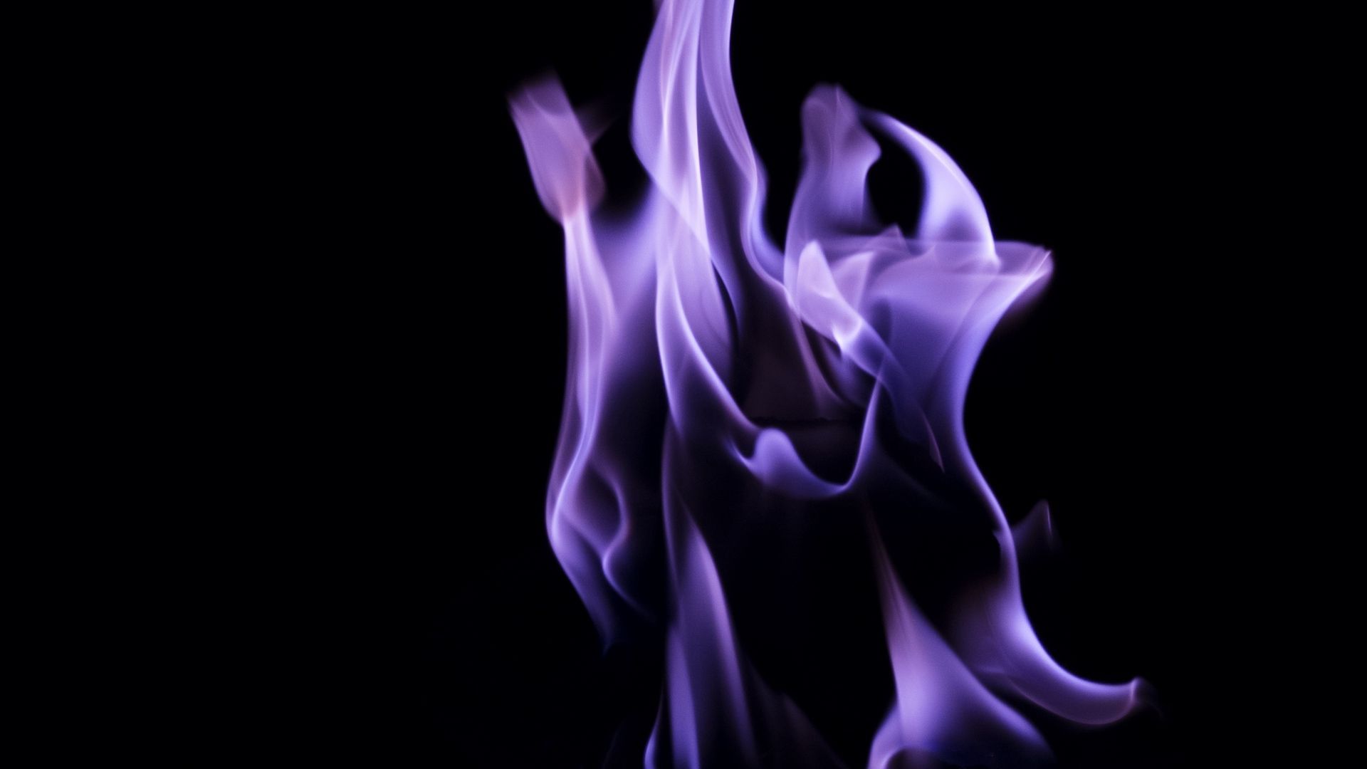 A purple flame burns against a black background. - Flames