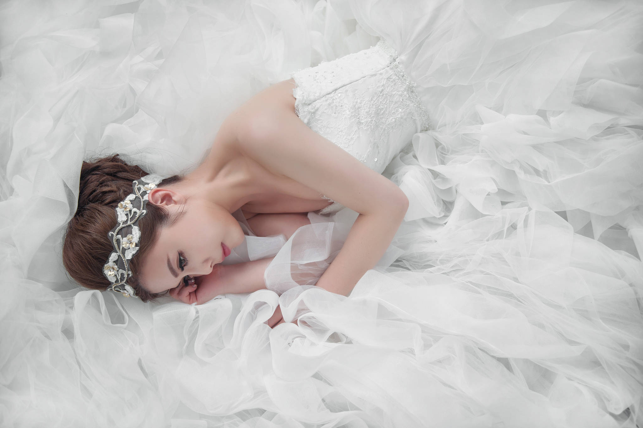 A woman laying on top of white fabric - Wedding