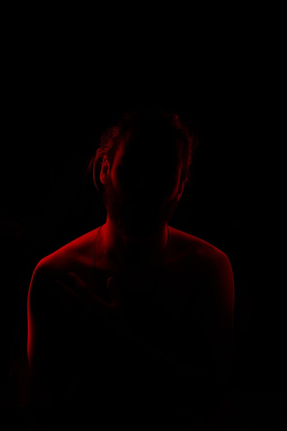 A woman in a dark room lit by red light. - Depression