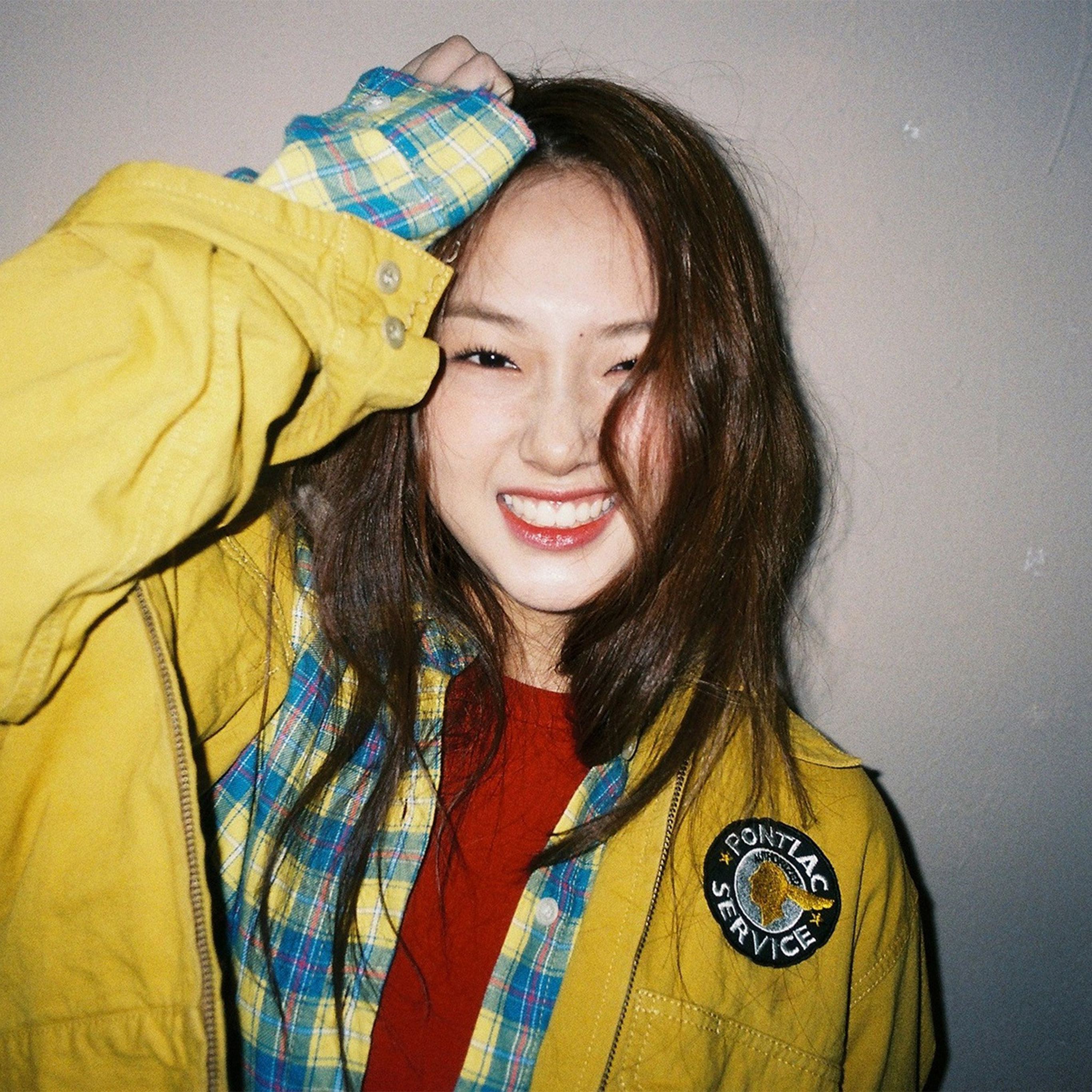 A woman wearing a yellow jacket and a red shirt smiling at the camera - Korean