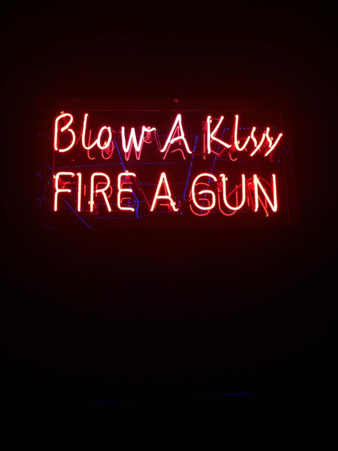 A red neon sign that says blow a kiss fire a gun. - Flames