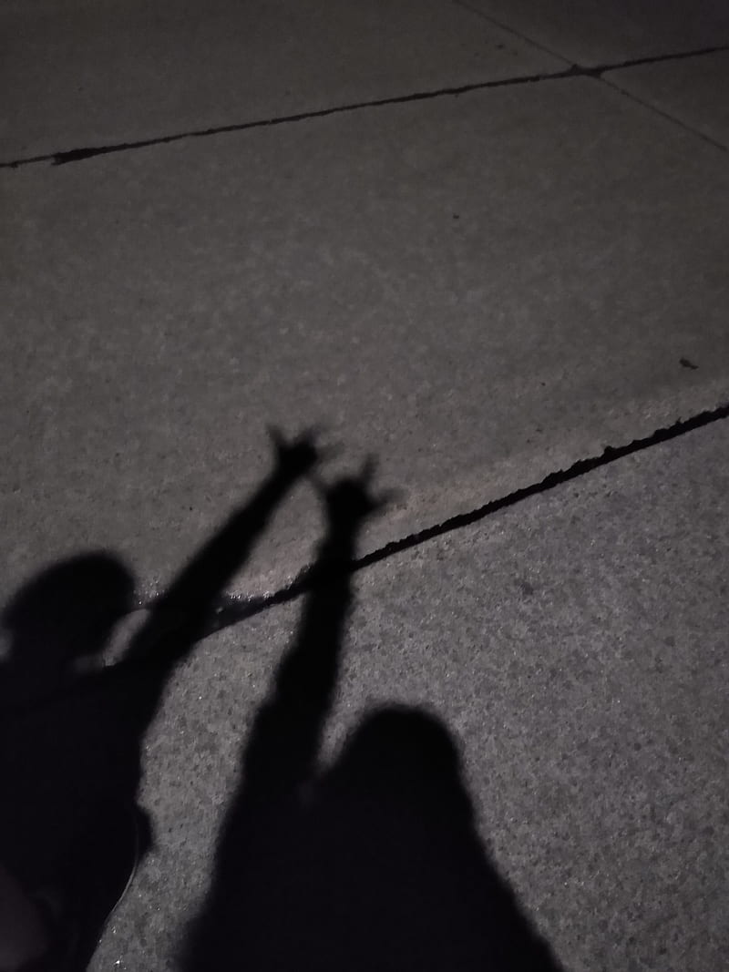 A shadow of a person holding their hands up in the air. - Shadow