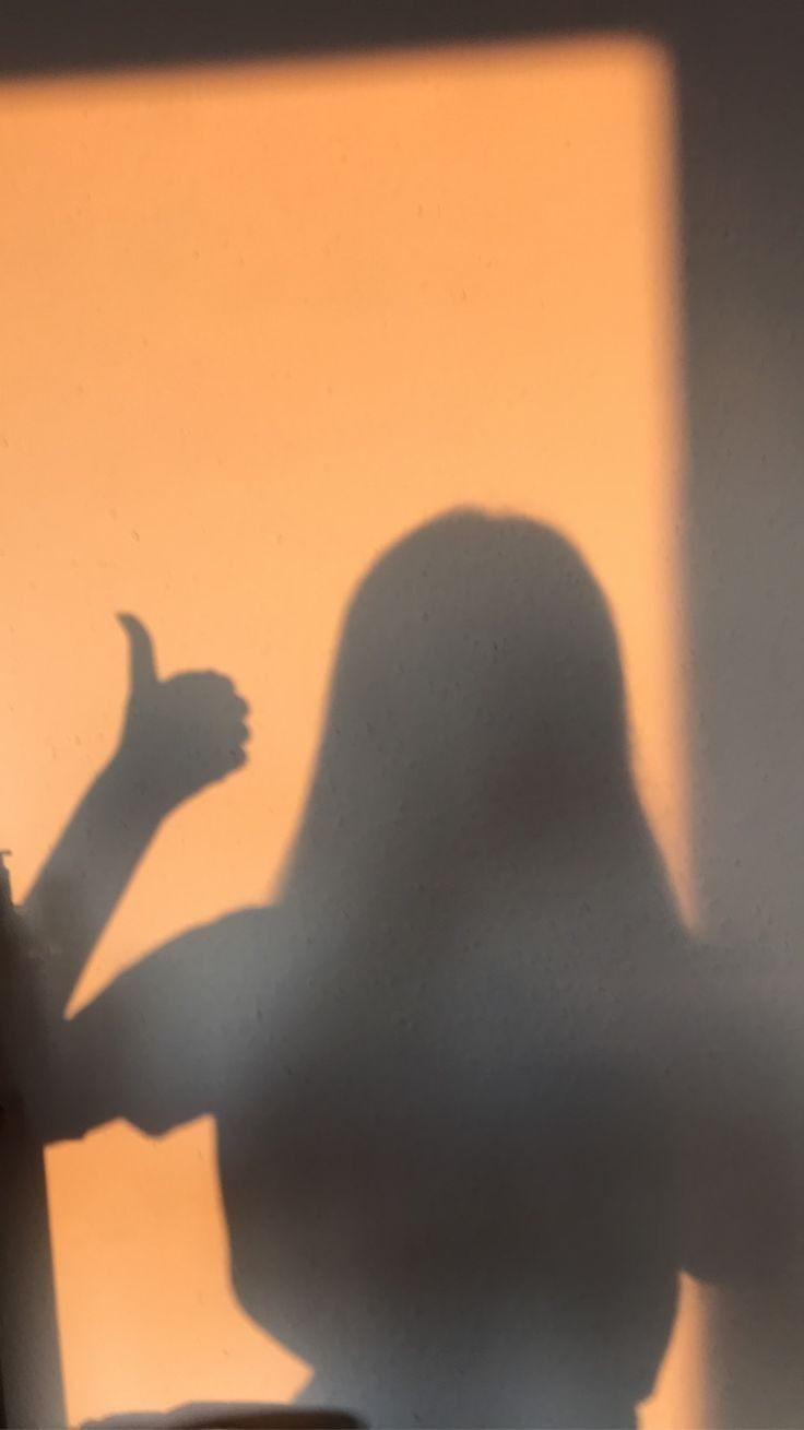 A shadow of a woman with long hair giving a thumbs up - Shadow