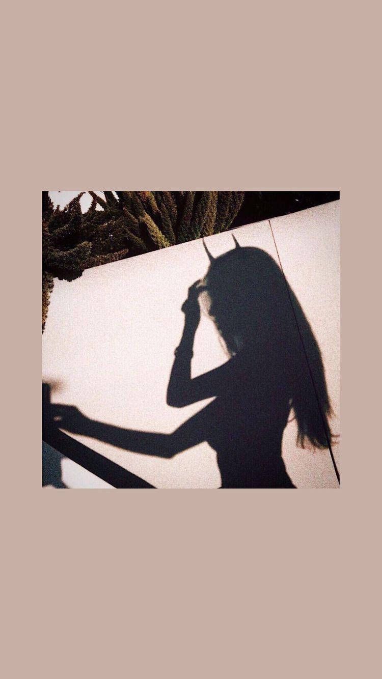 A woman's shadow on a wall, with her hand on her head. - Shadow