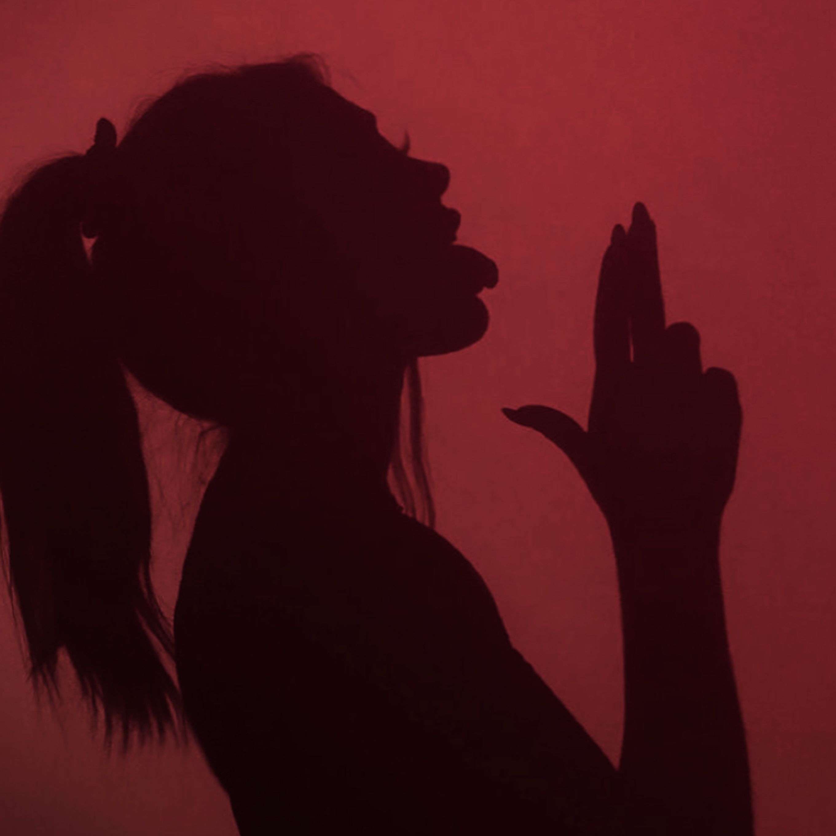 A woman in silhouette making the peace sign - Shadow